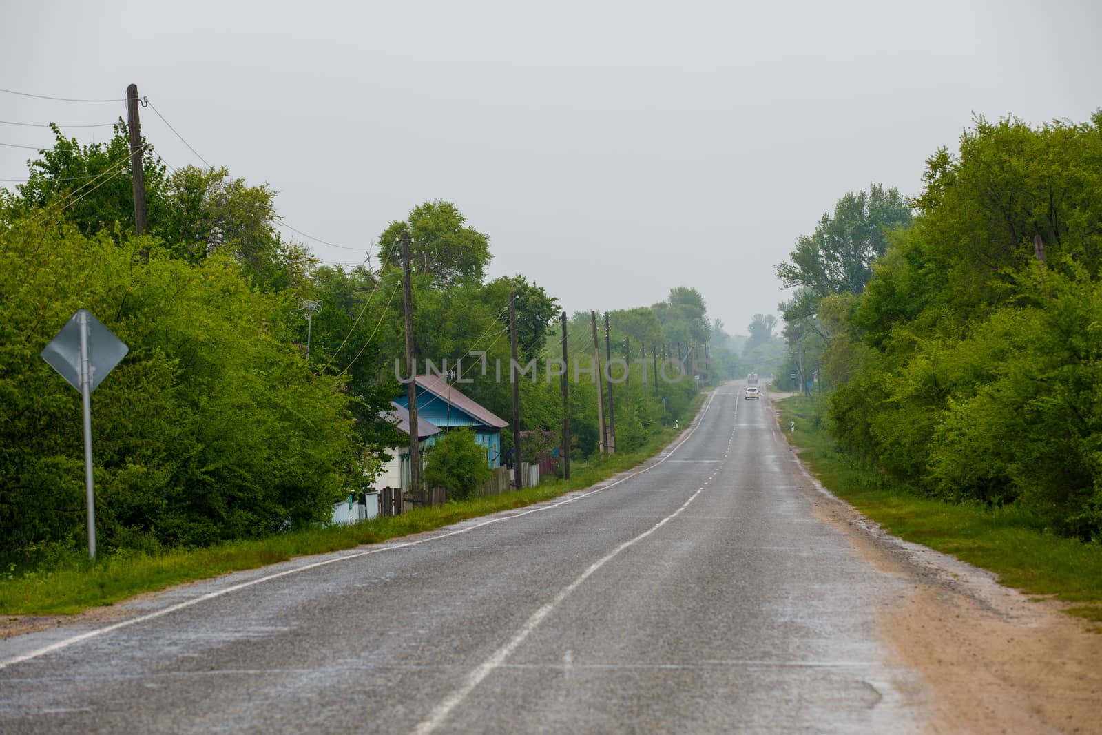 An asphalt road passes by a village with wooden houses by PrimDiscovery