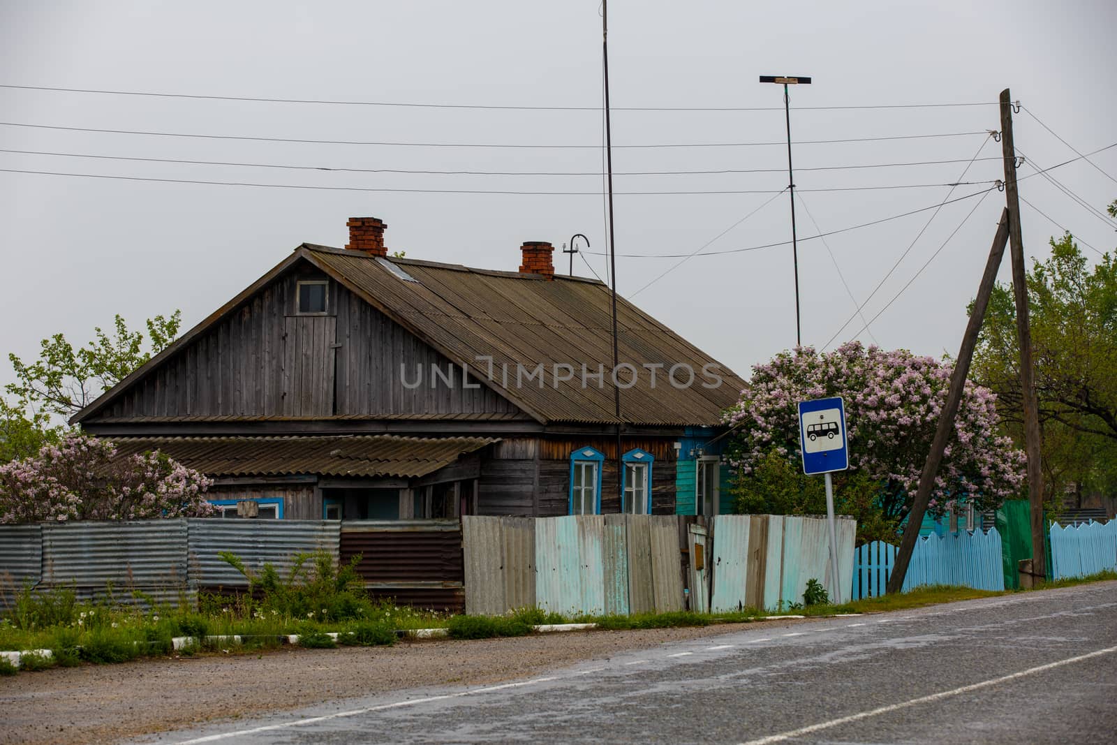 An old wooden village house stand behind a wooden palisade.