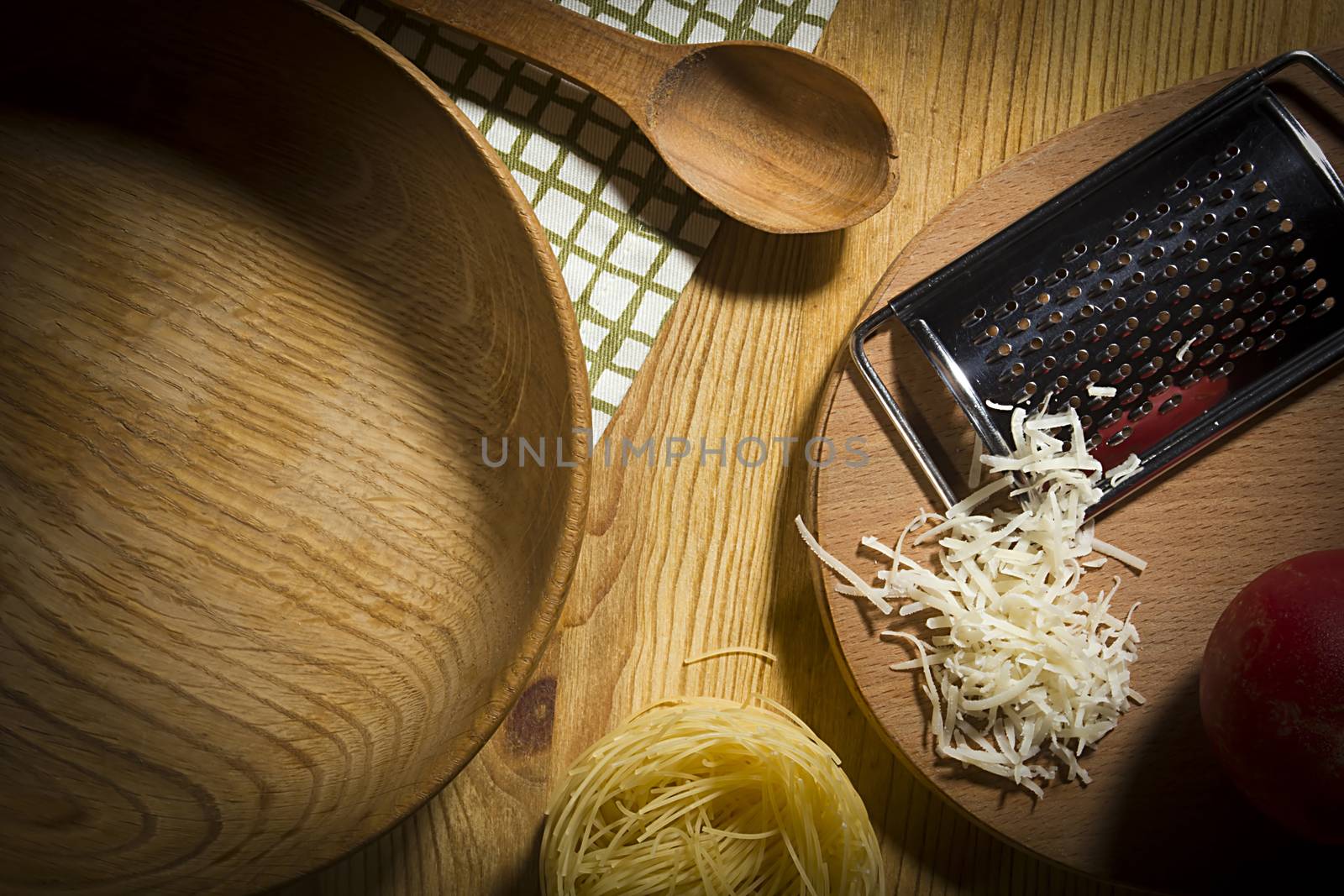 Wooden utensils and metal grater with ingredients for making pasta