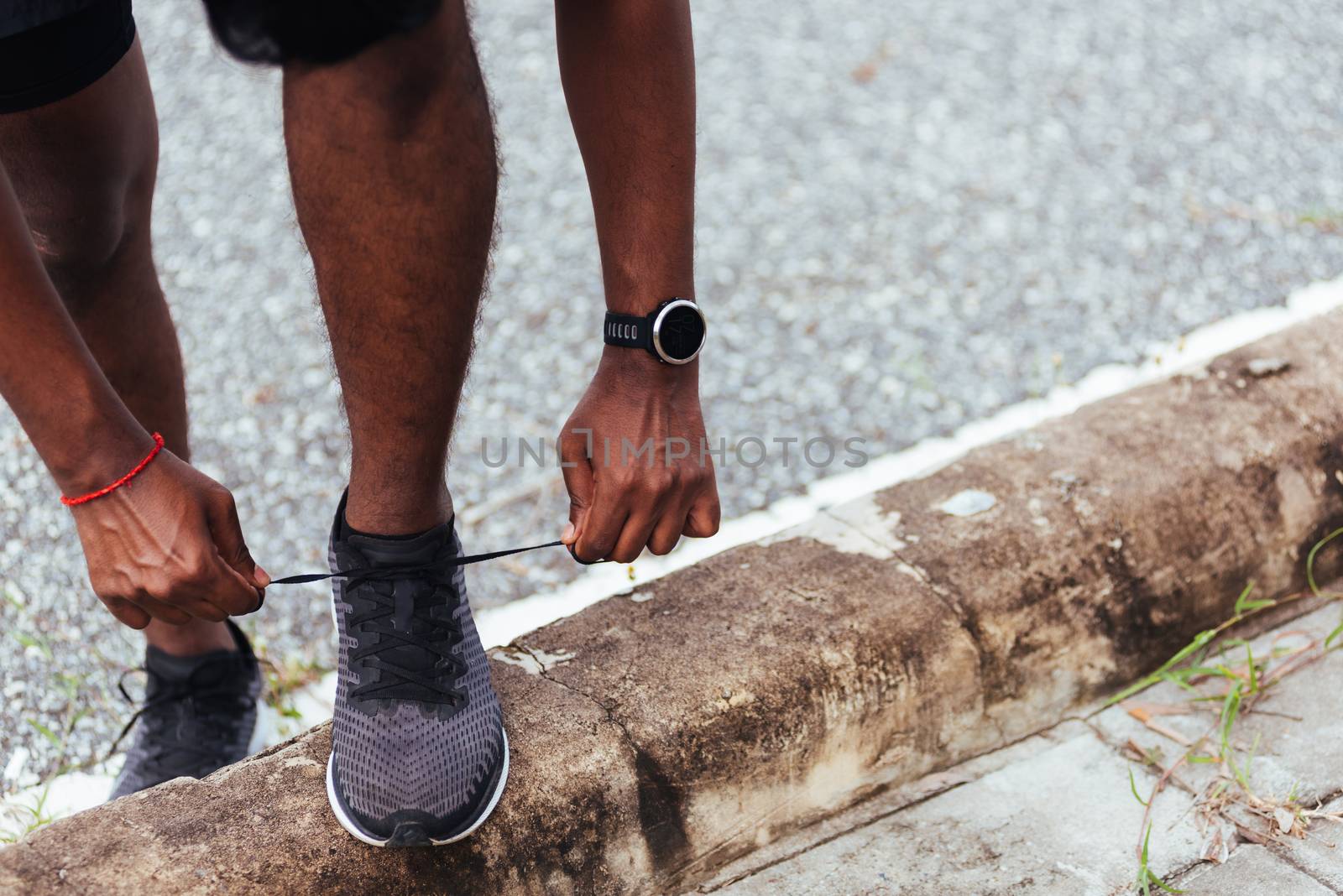 runner black man wear watch stand step on the footpath trying sh by Sorapop