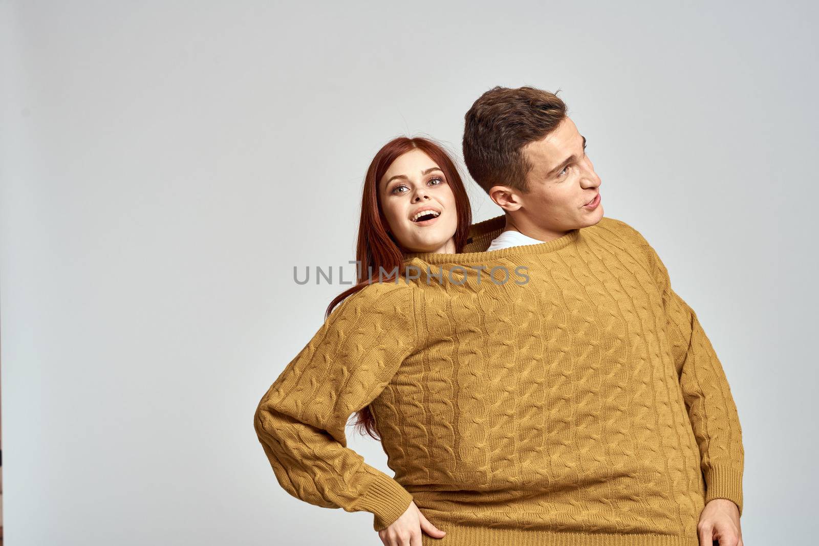 couple in yellow sweater posing against light background cropped view by SHOTPRIME