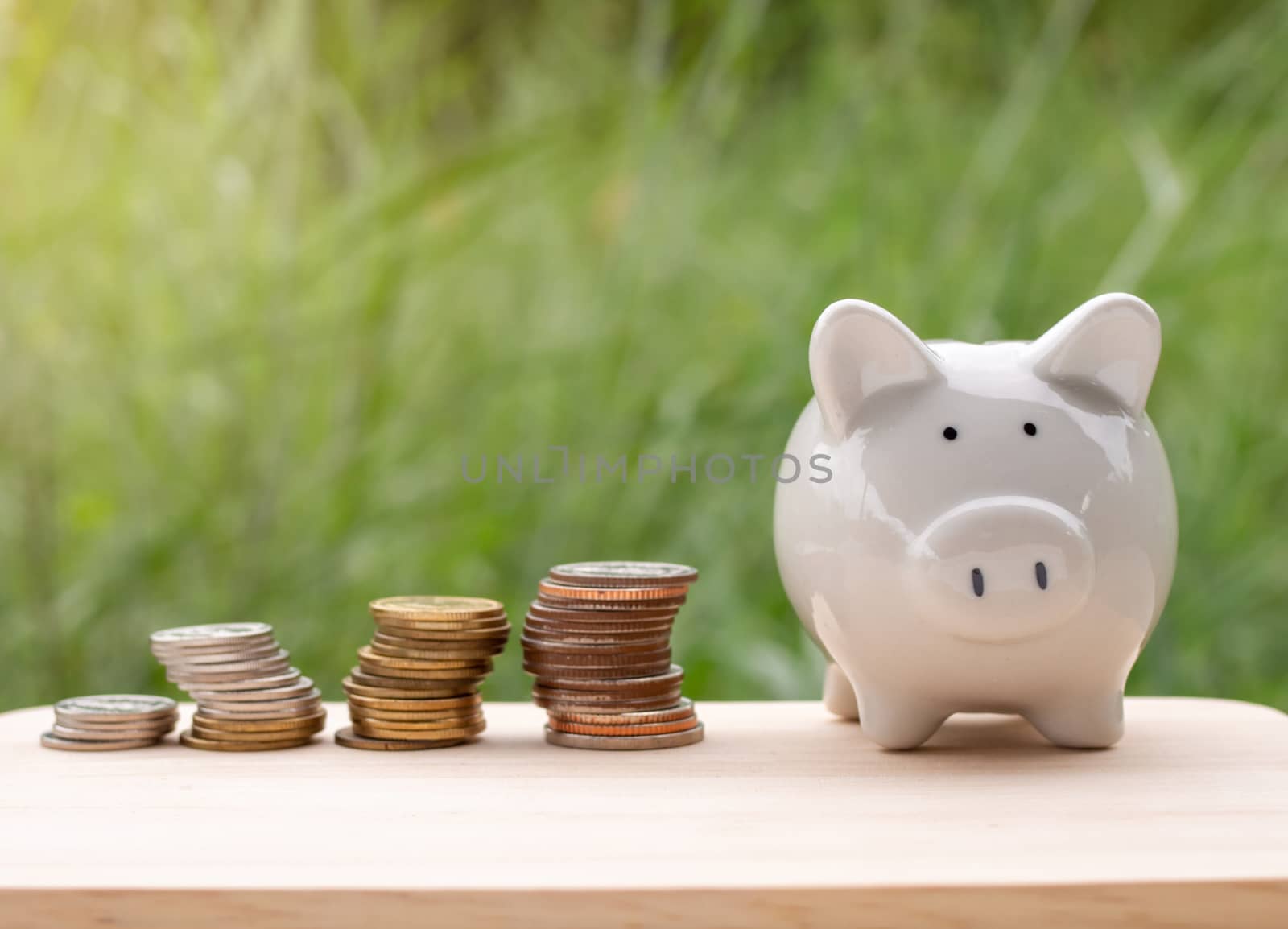 Piggy bank and silver coin placed on the wooden table. On natura by Unimages2527