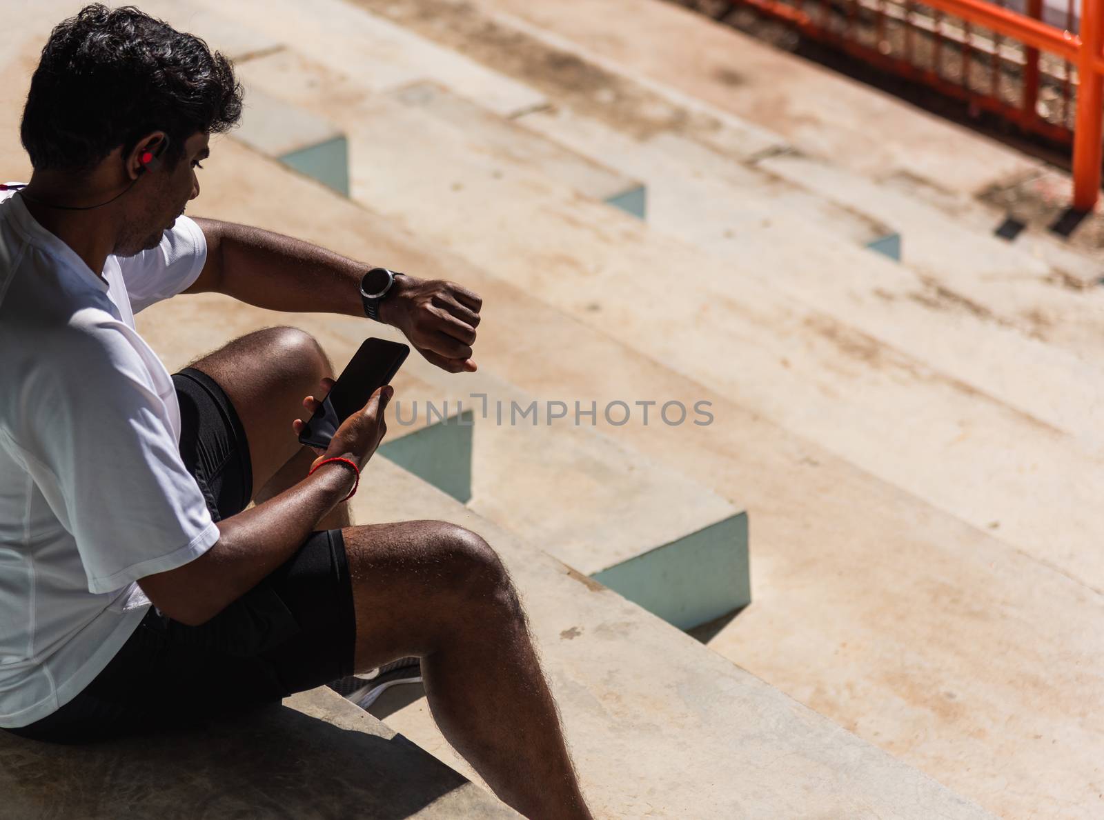 Close up Asian young athlete sport runner black man wear modern time smart watch and sync to a smartphone check running result after a training run at the outdoor, healthy exercise workout technology