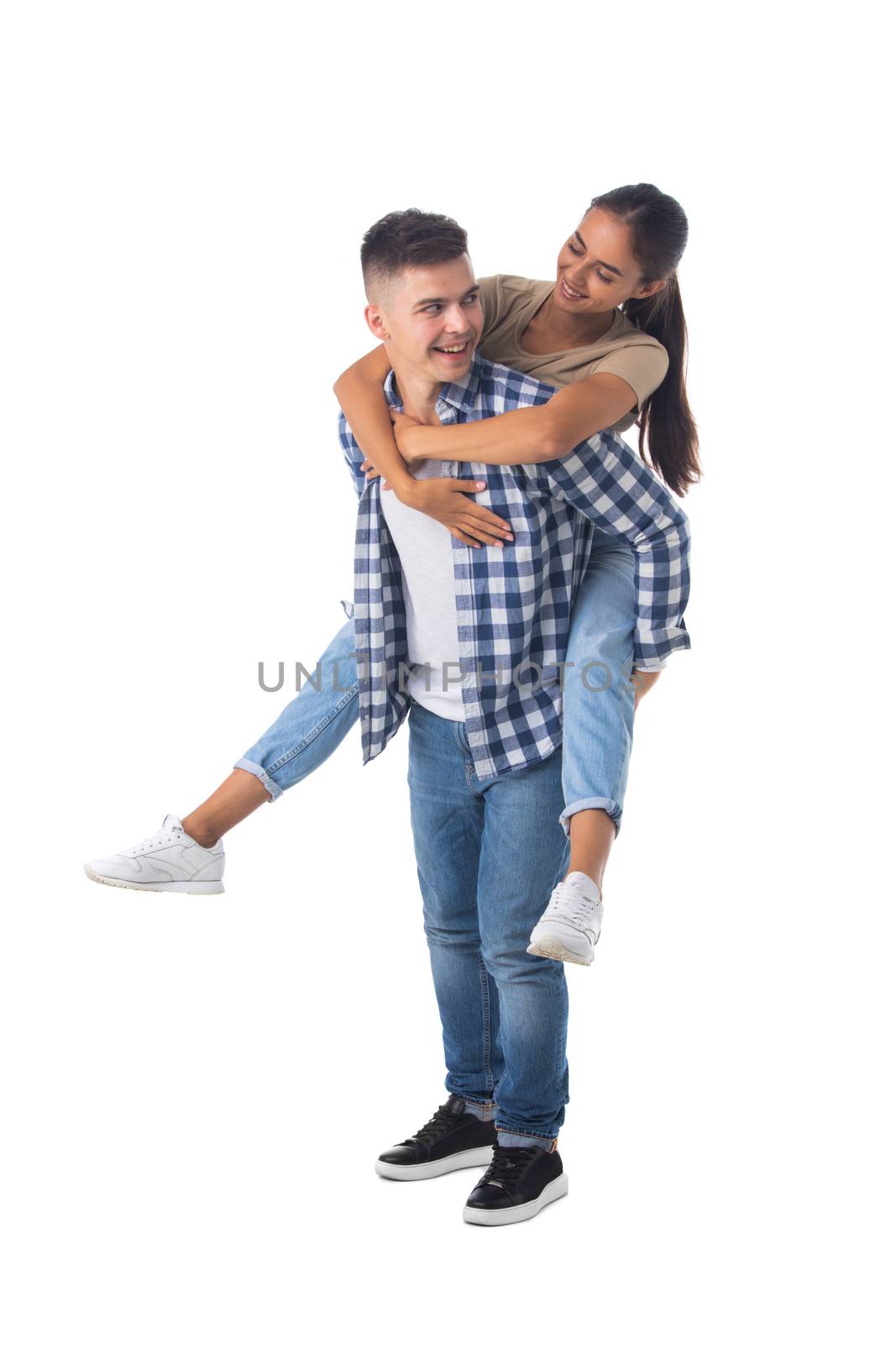 Young happy couple with her at piggiback ride isolated on white background, casual people