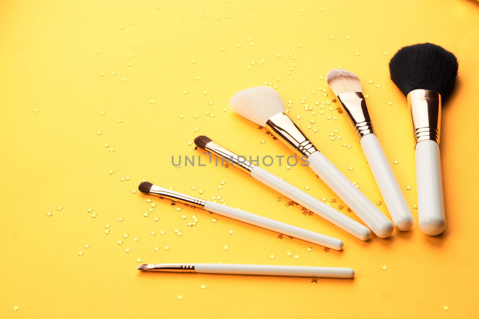 Makeup brushes with sparkles on a yellow background professional cosmetics by SHOTPRIME