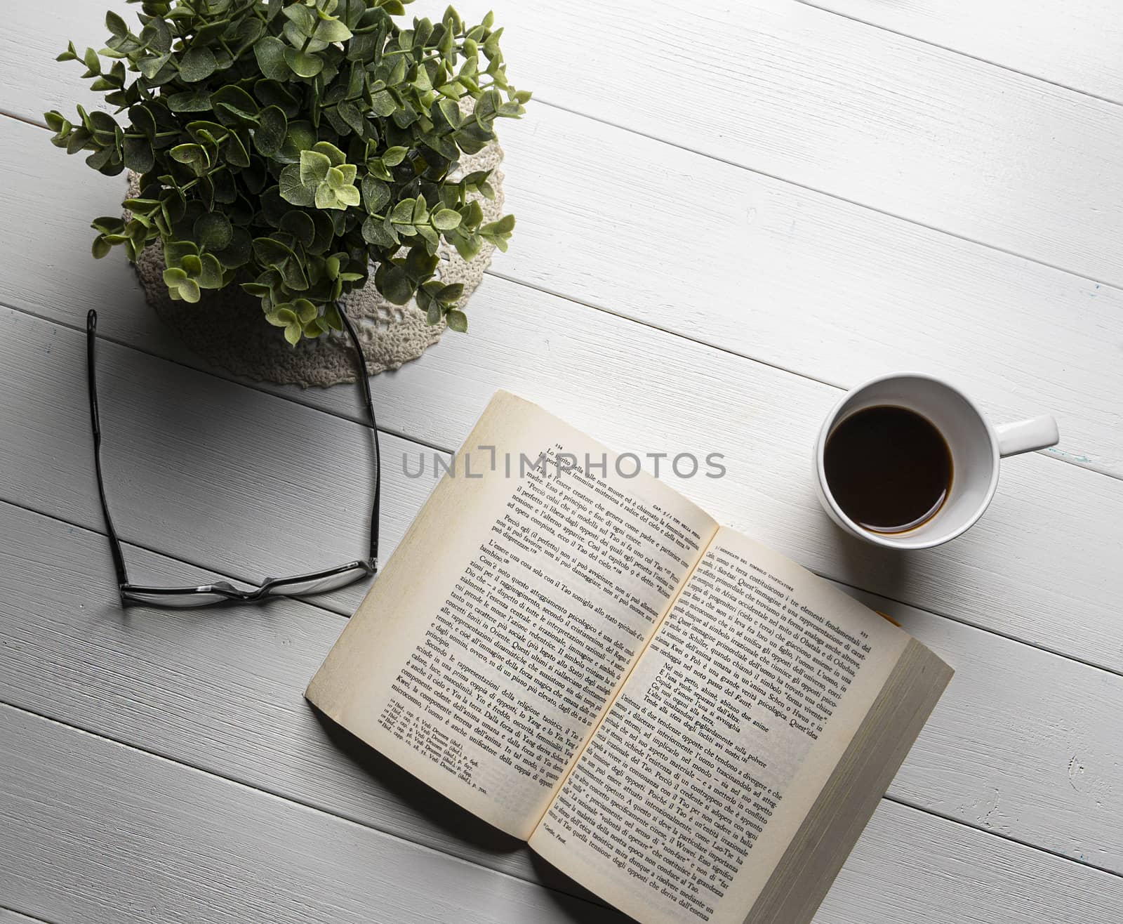 A book open on a white wooden table with a coffee cup