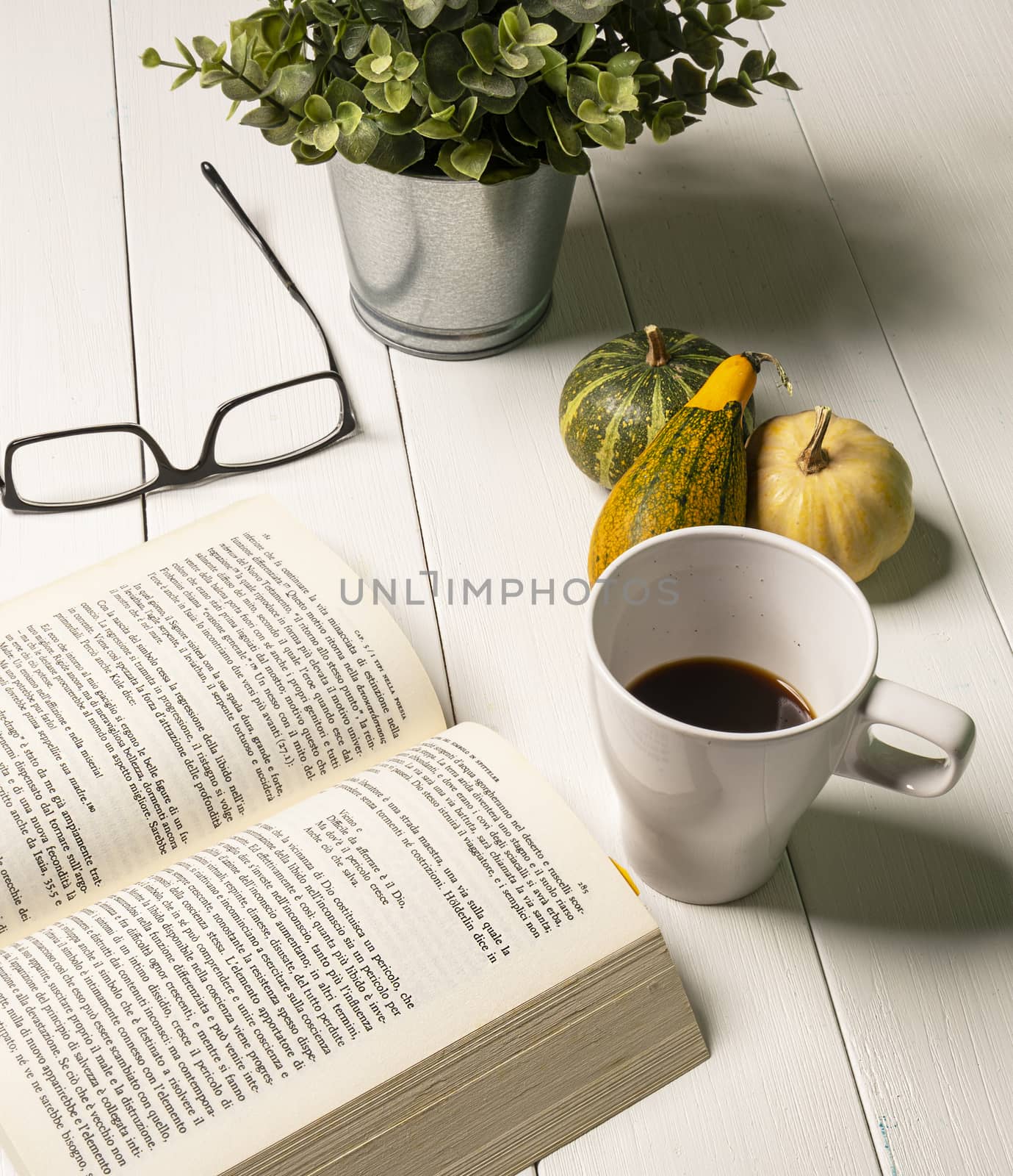 A book open on a white wooden table with a coffee cup