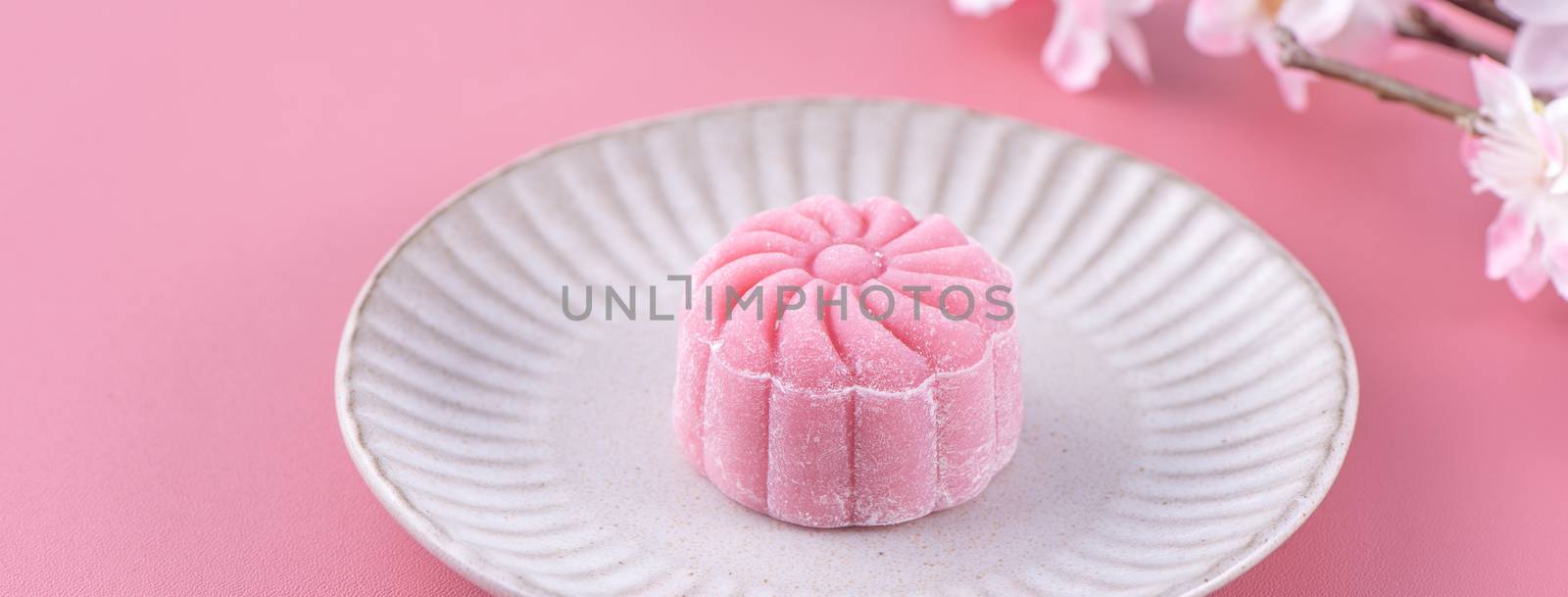 Colorful snow skin moon cake, sweet snowy mooncake, traditional savory dessert for Mid-Autumn Festival on pastel pale pink background, close up.