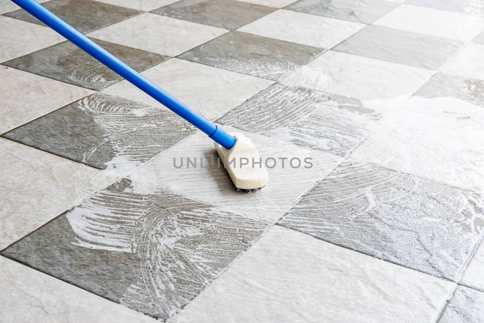 Clean the tile floor with a long-handled floor brush.