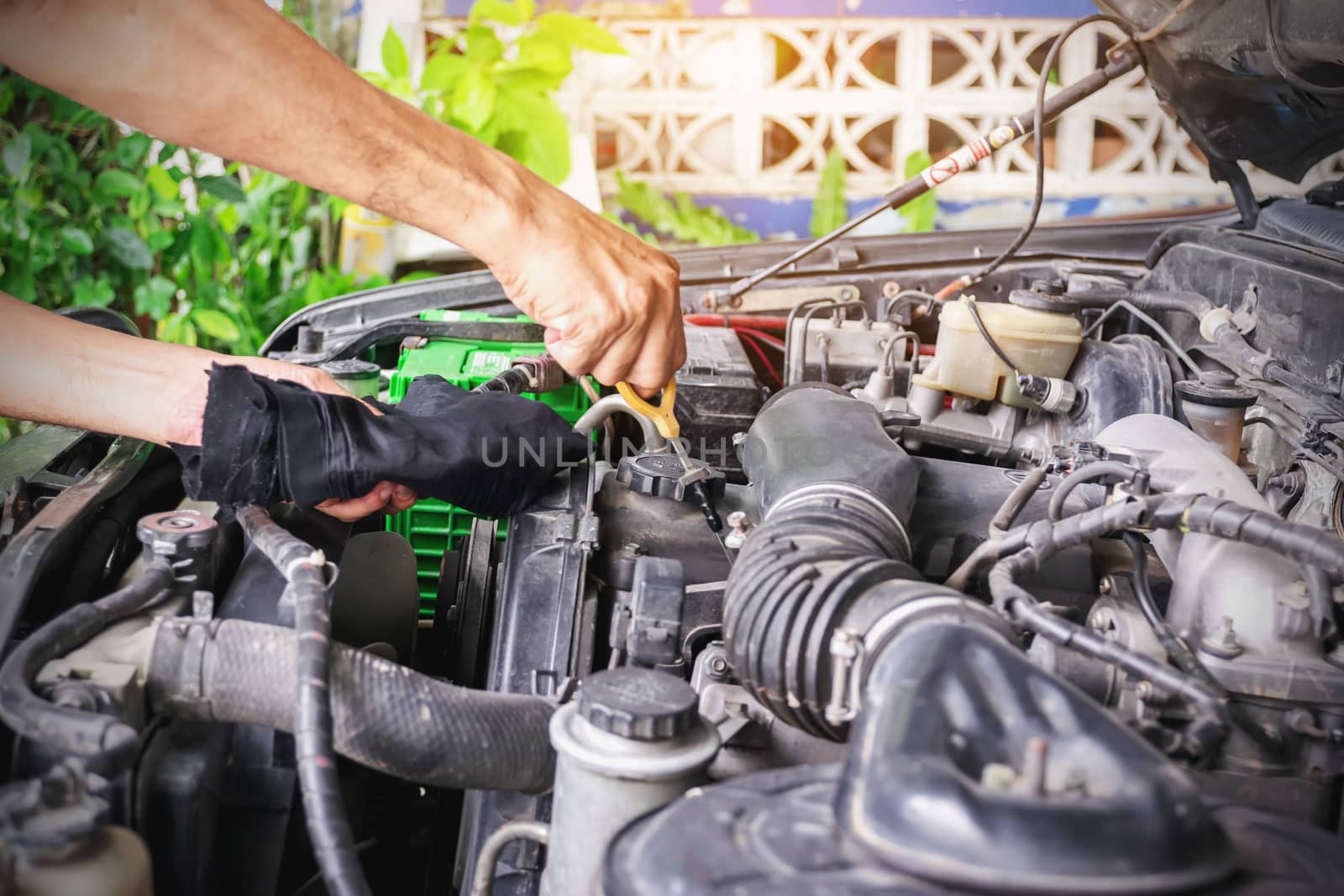 Cars mechanic is checking the level of engine oil from the engine oil level gauge of the car, Automotive industry and garage concepts.