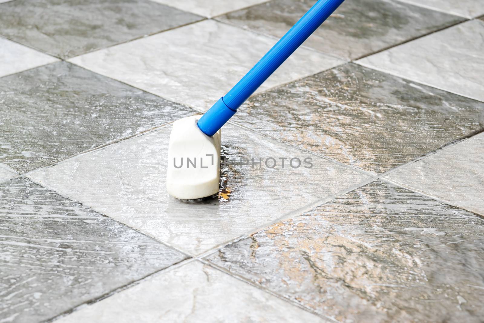 Clean the tile floor with a long-handled floor brush.