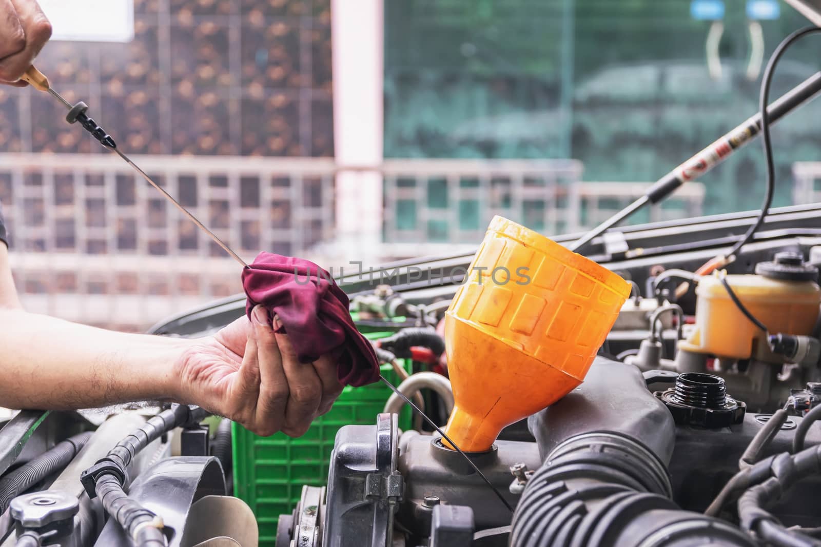 Cars mechanic is checking the level of engine oil from the engine oil level gauge of the car, Automotive industry and garage concepts.