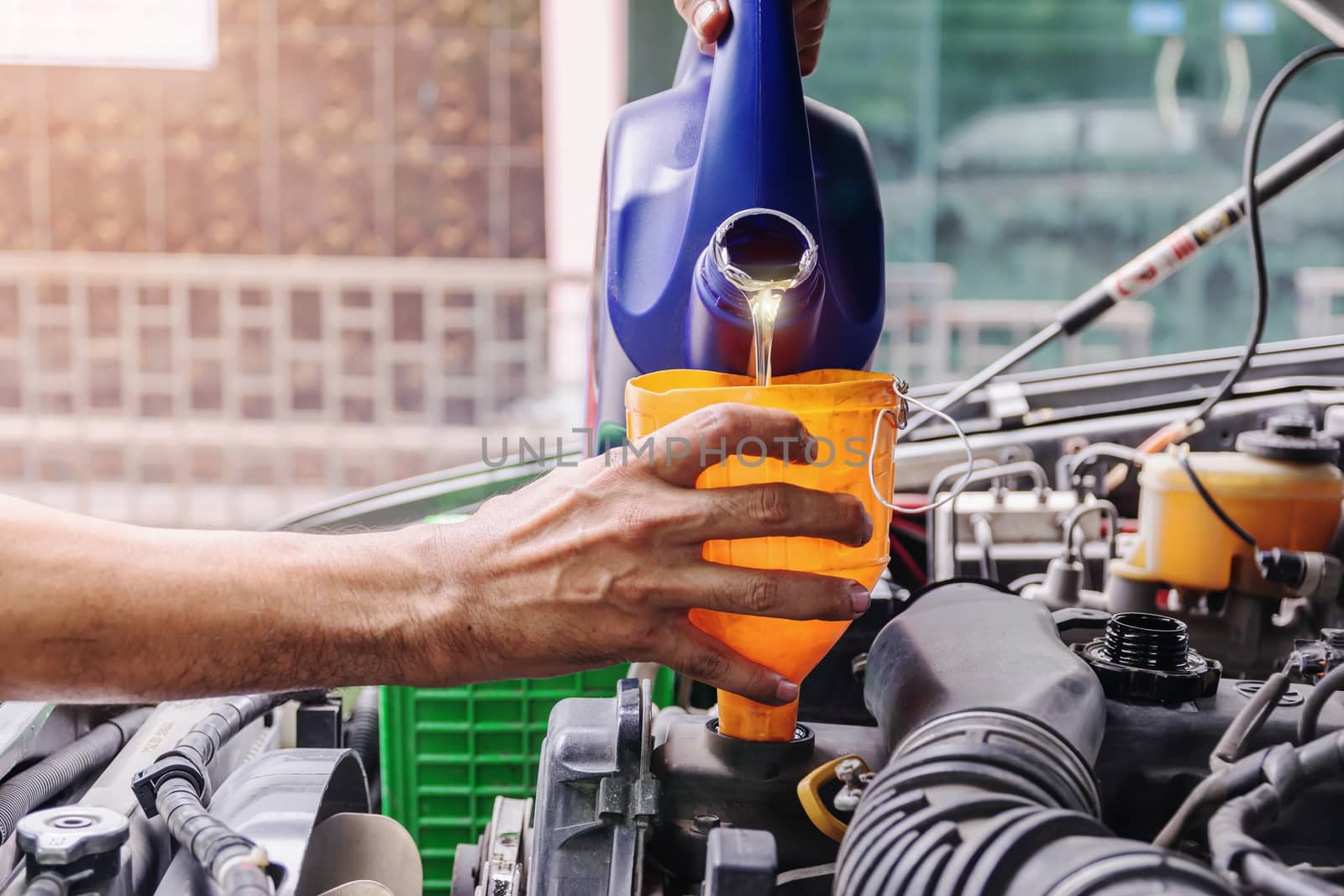 Car mechanic is adding oil to the engine, Automotive industry and garage concepts.