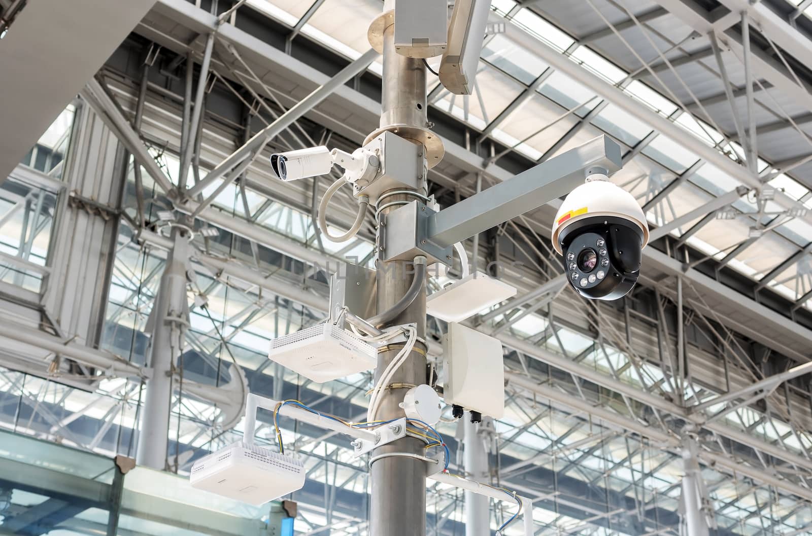 CCTV cameras, wireless signal distribution equipment and speakers mounted on poles inside the building.