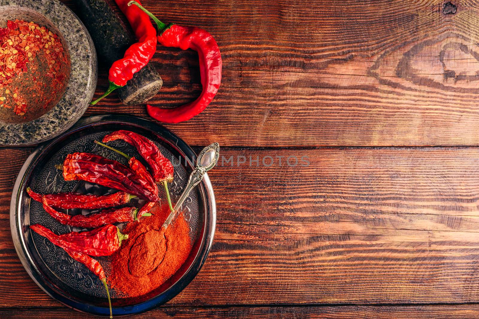 Fresh, dried and ground red chili peppers over wooden surface. Copy space