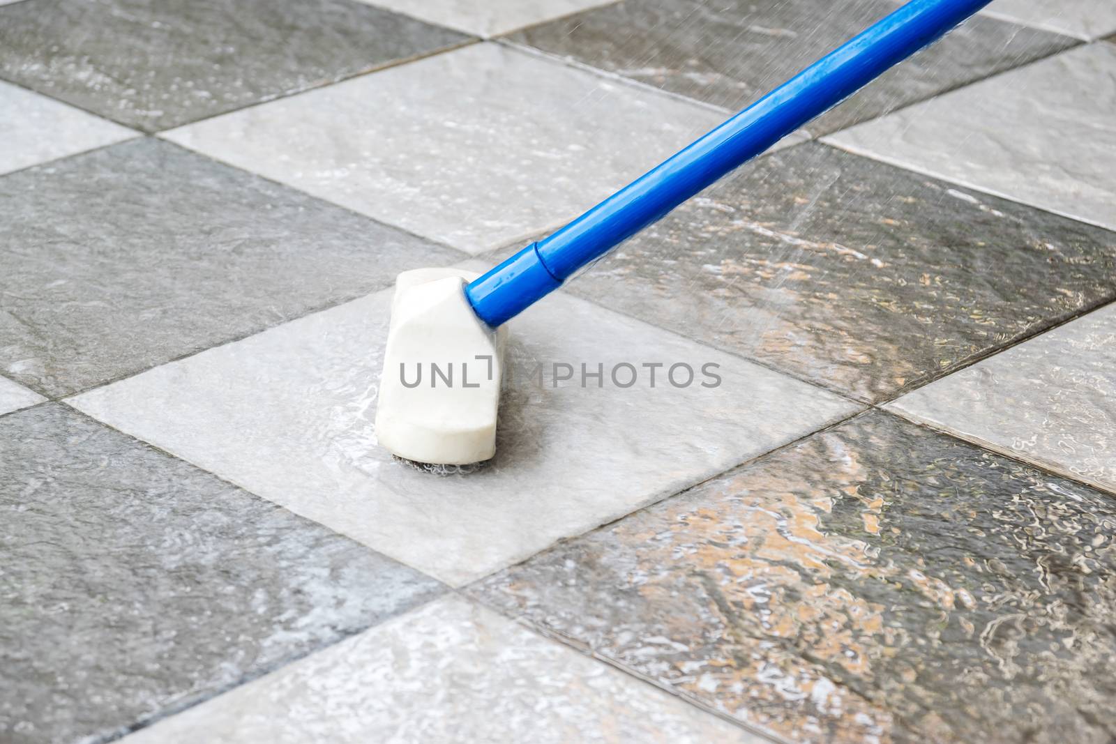 Cleaning the tile floor with floor scrubber brush.