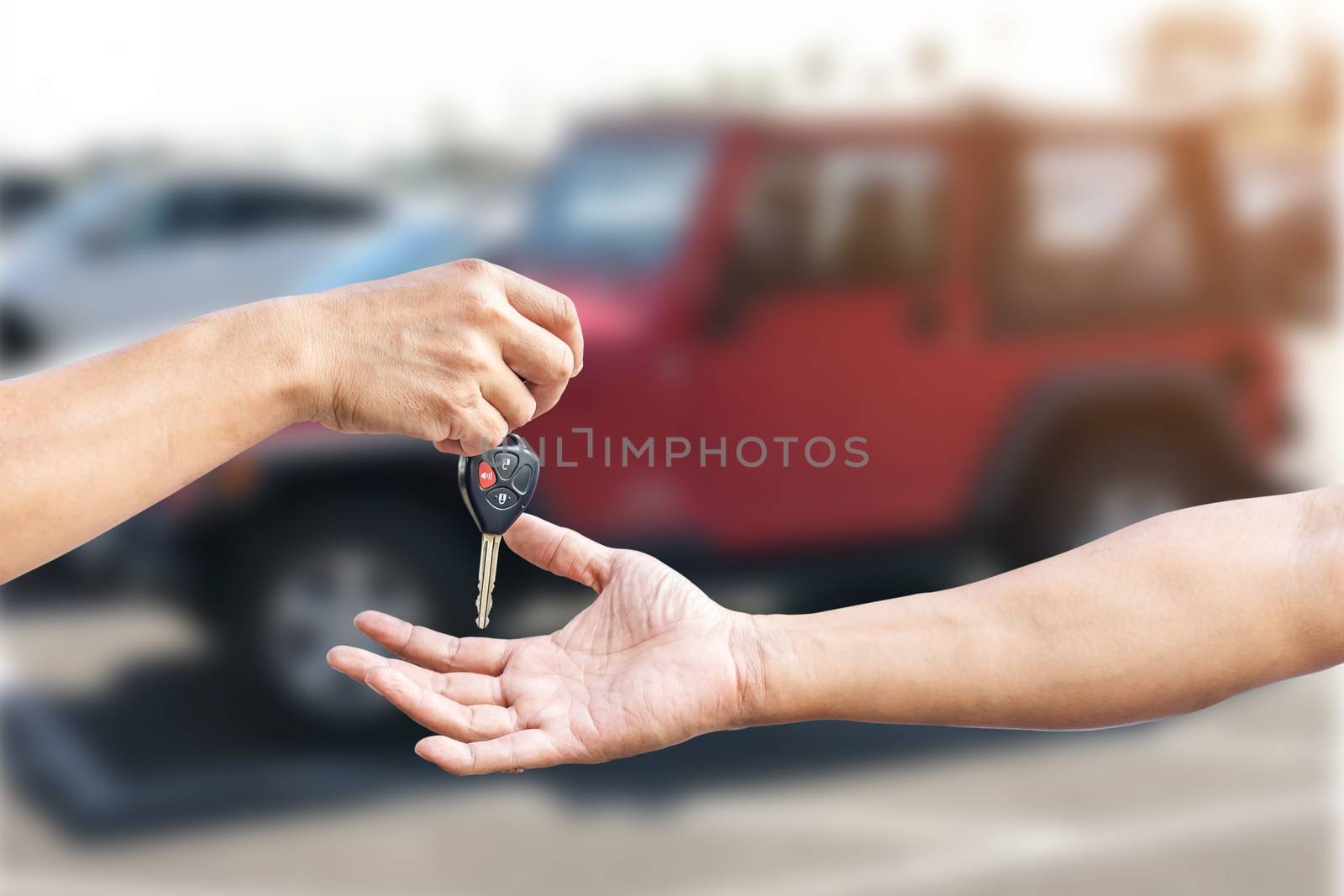 Closeup a man's hand is delivering a car key to another man's hand, use for the concept of car repair industry, insurance or automobile trading.