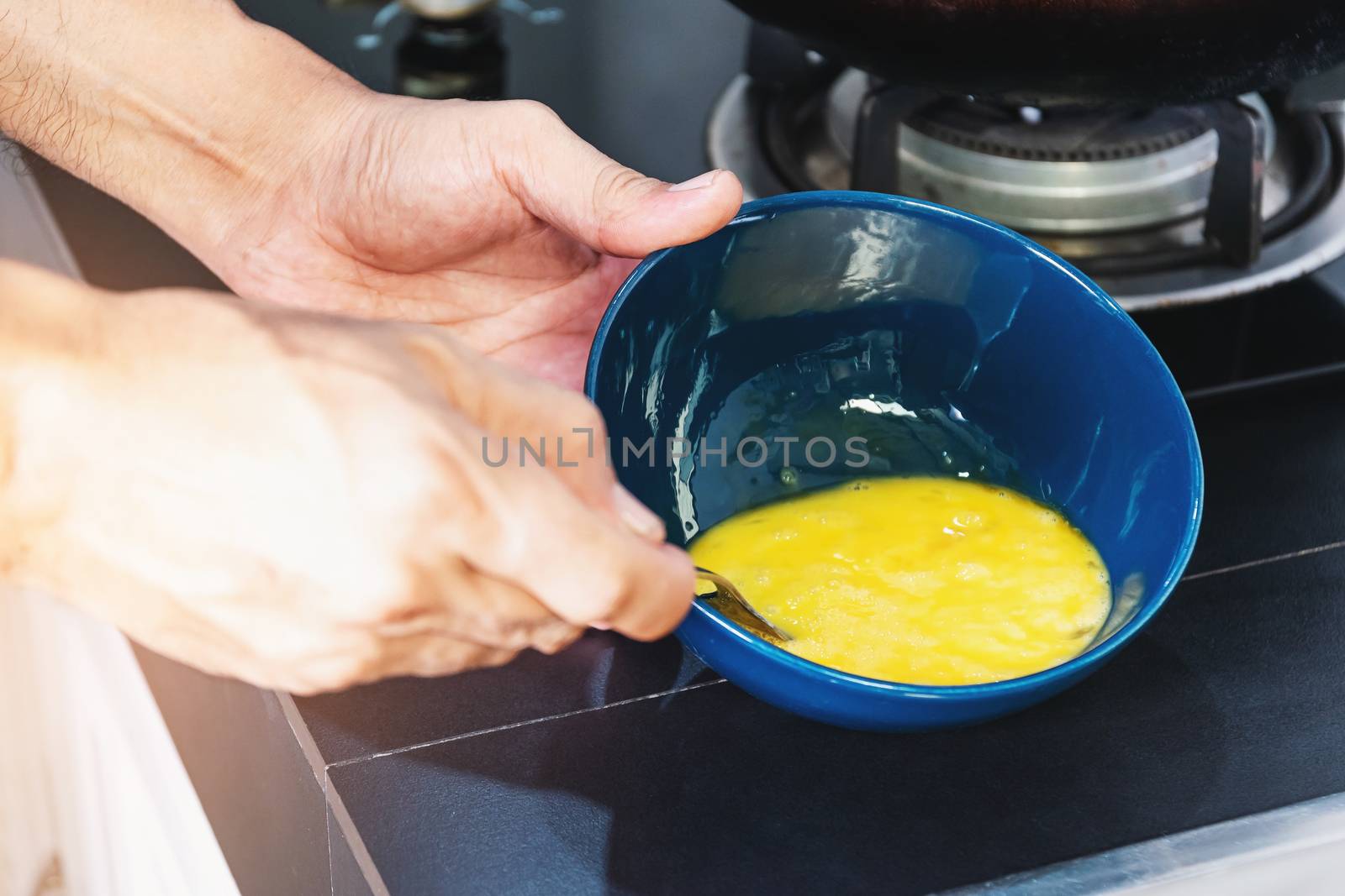 Close men's hand using a spoon beat the eggs in a ceramic cup to cook.