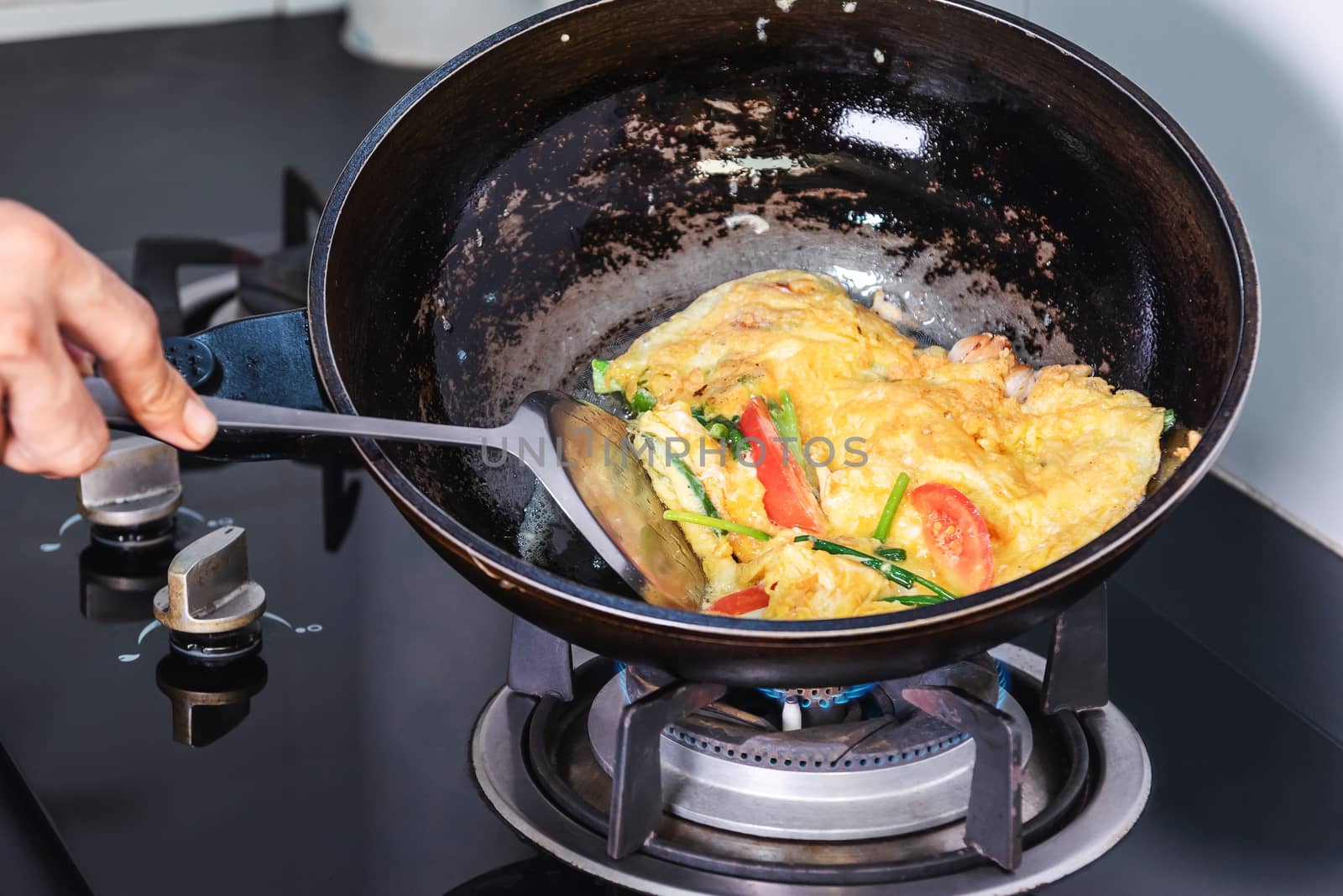 Frying eggs in a frying pan with heat from a gas stove fire in the kitchen.