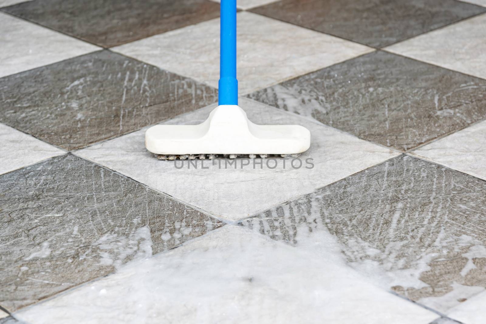 Cleaning the tile floor with floor scrubber brush.