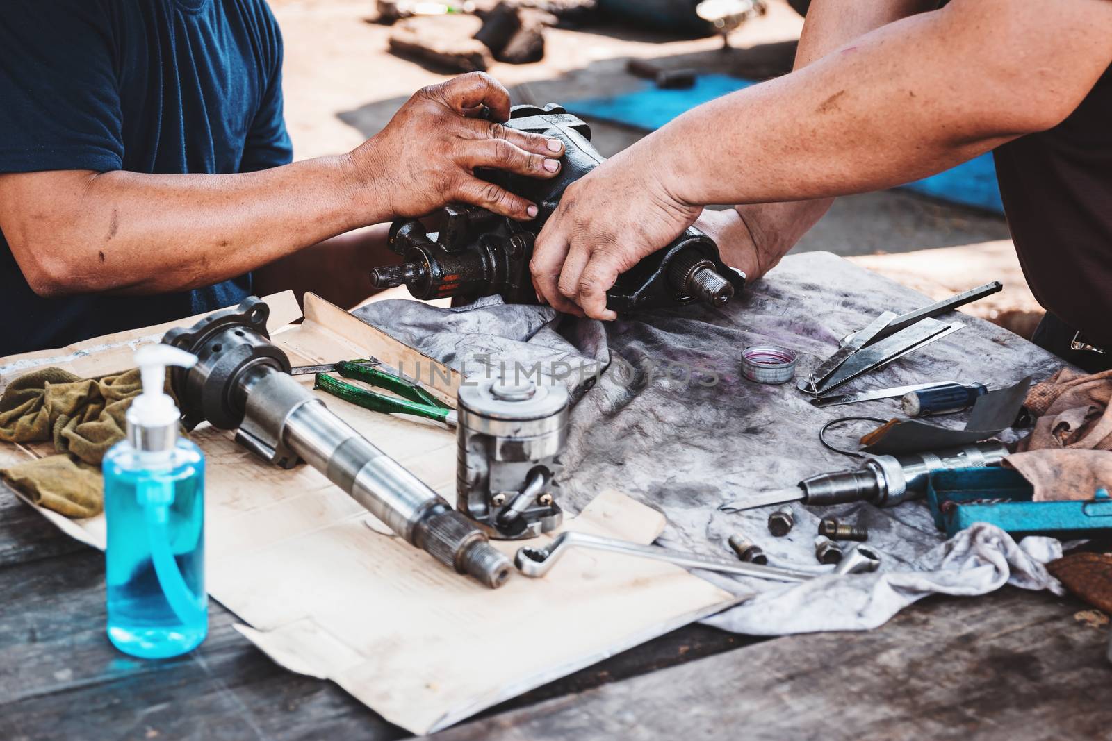 Technicians are helping to assemble the car power steering gearbox.