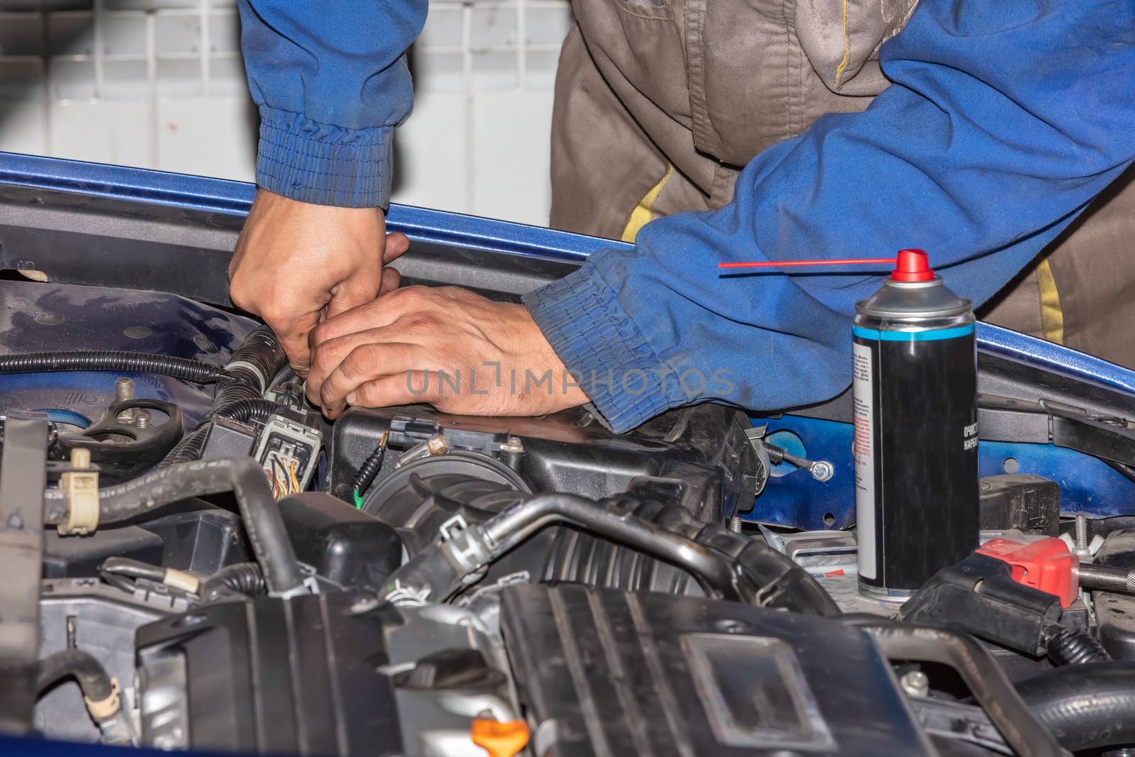 Repairman Working with dirty hands and uniform fixing car engine at service shop. Mechanic man hands repair and overhaul car engine. Mechanic wearing blue uniform