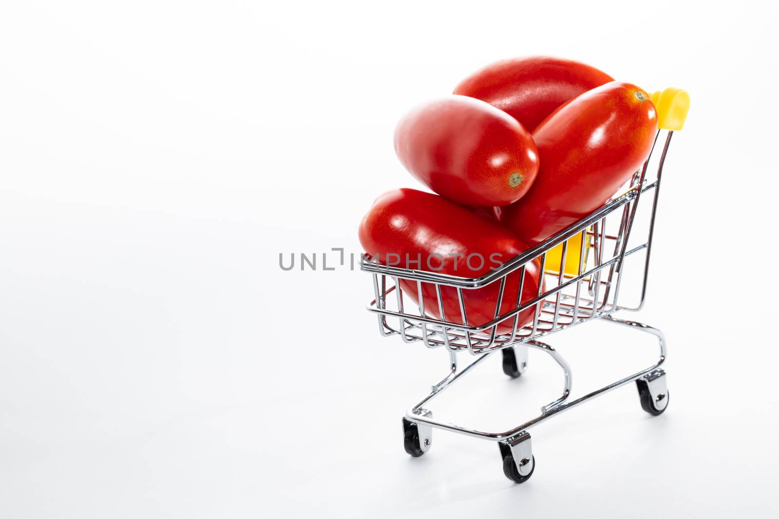High angle shot of tomatoes in shopping cart isolated on white background. Ripe tasty red tomatos in shopping cart. Tomato trading concept. Online shopping concept. Copy space.