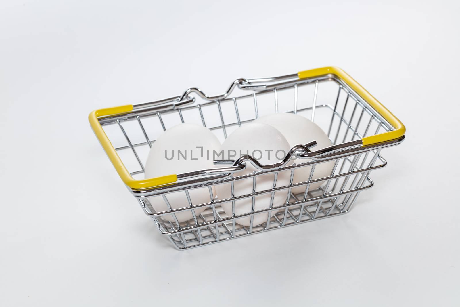 Fresh eggs in a shopping basket. High angle shot. Basket hands down. Shopping, purchasing, and food delivery concept. White background. Close up shot. Isolated.