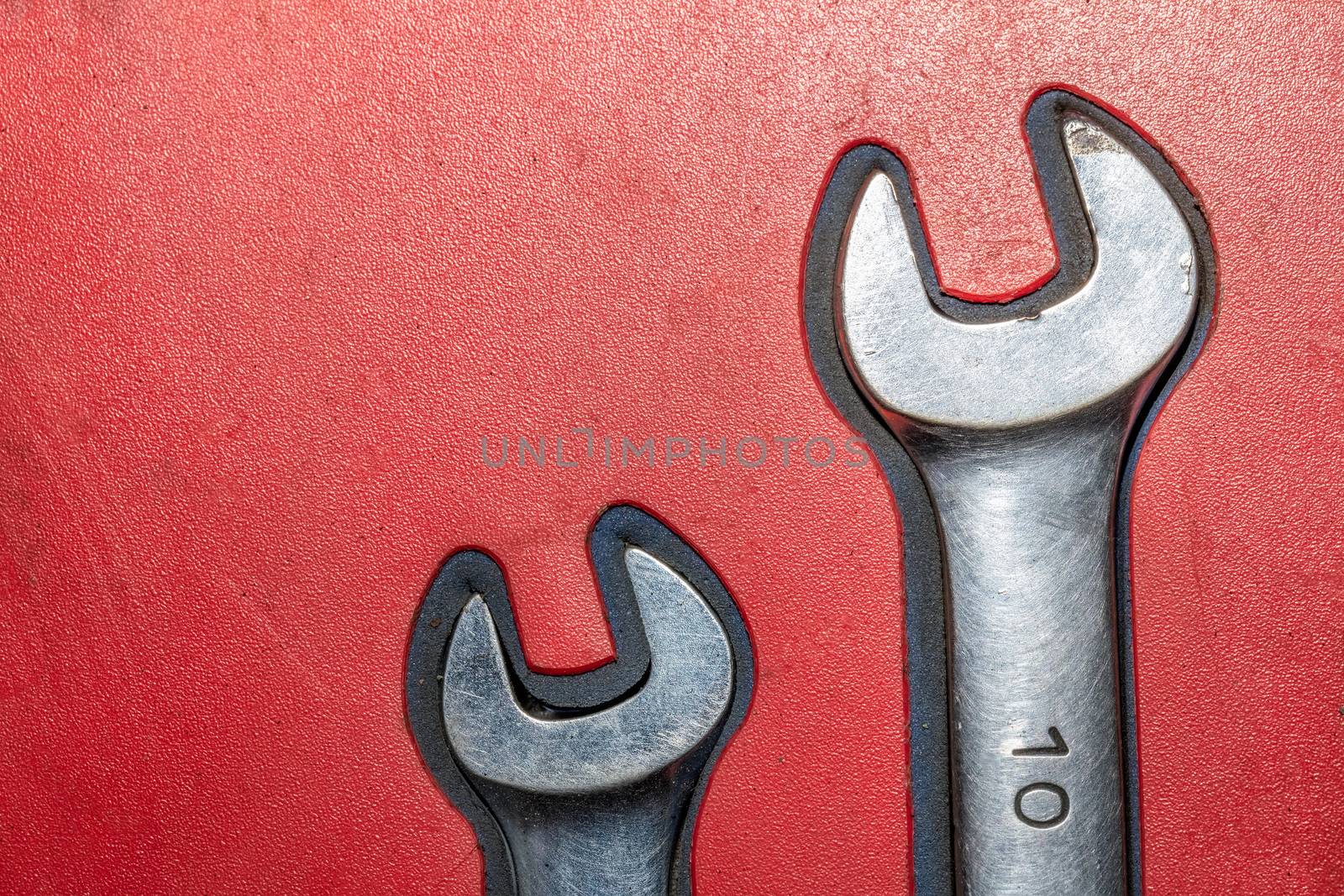 Close-up of two old chrome wrenches on red background.