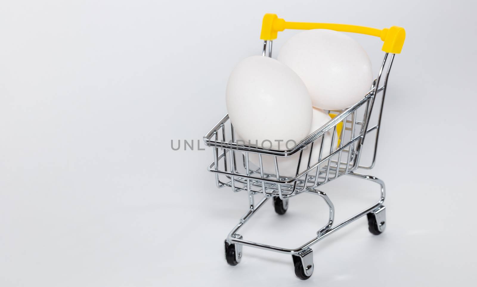 Fresh eggs in a shopping cart. High angle shot. Shopping, purchasing, and food delivery concept. White background. Close-up shot. Isolated. Copy space.