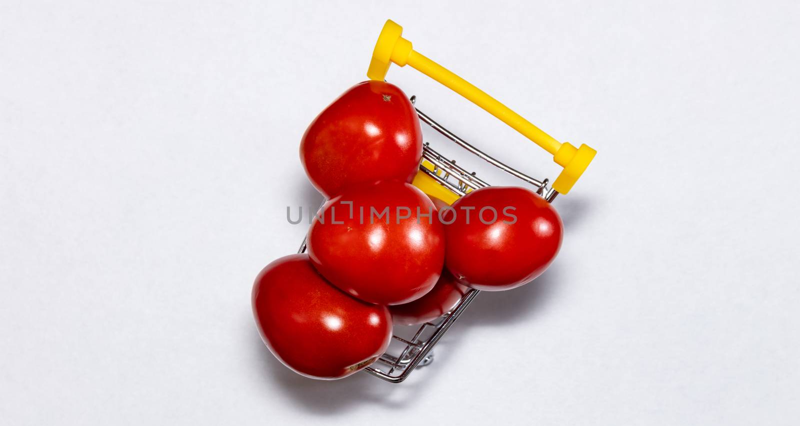 Shot of tomatoes in shopping cart isolated on white background. Top view. Ripe tasty red tomatos in shopping cart. Tomato trading concept. Online shopping concept. Copy space.