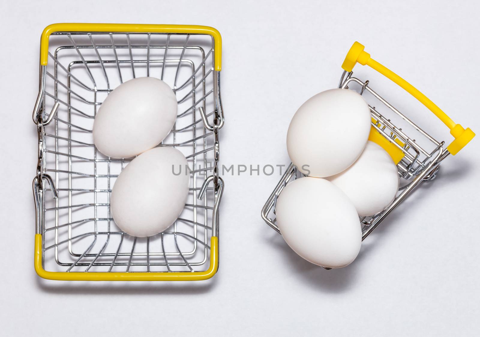 Fresh eggs in a shopping cart and a basket next to it. Top view. Shopping, purchasing, and food delivery concept. by DamantisZ