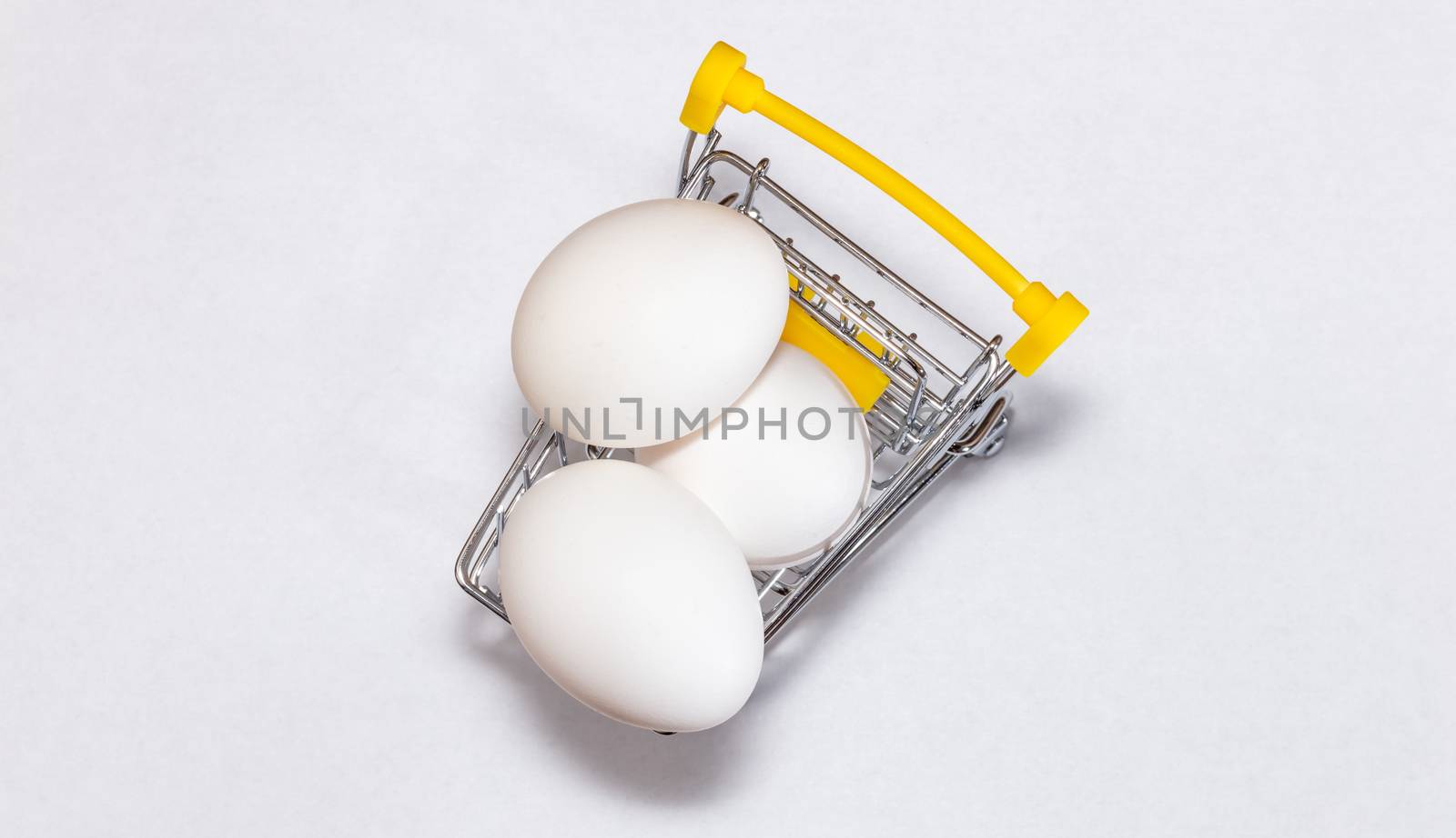 Fresh eggs in a shopping cart. Top view. Shopping, purchasing, and food delivery concept. White background. Close up shot. Isolated. Copy space.