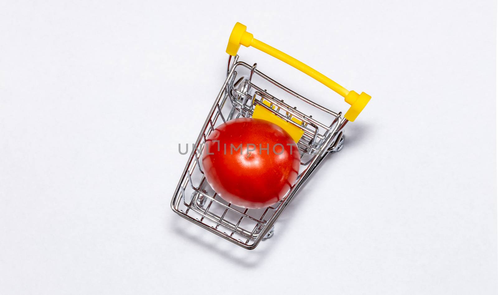 Shot of a single tomato in shopping cart isolated on white background. Top view. Ripe tasty red tomatos in shopping cart. Tomato trading concept. Online shopping concept. Copy space.