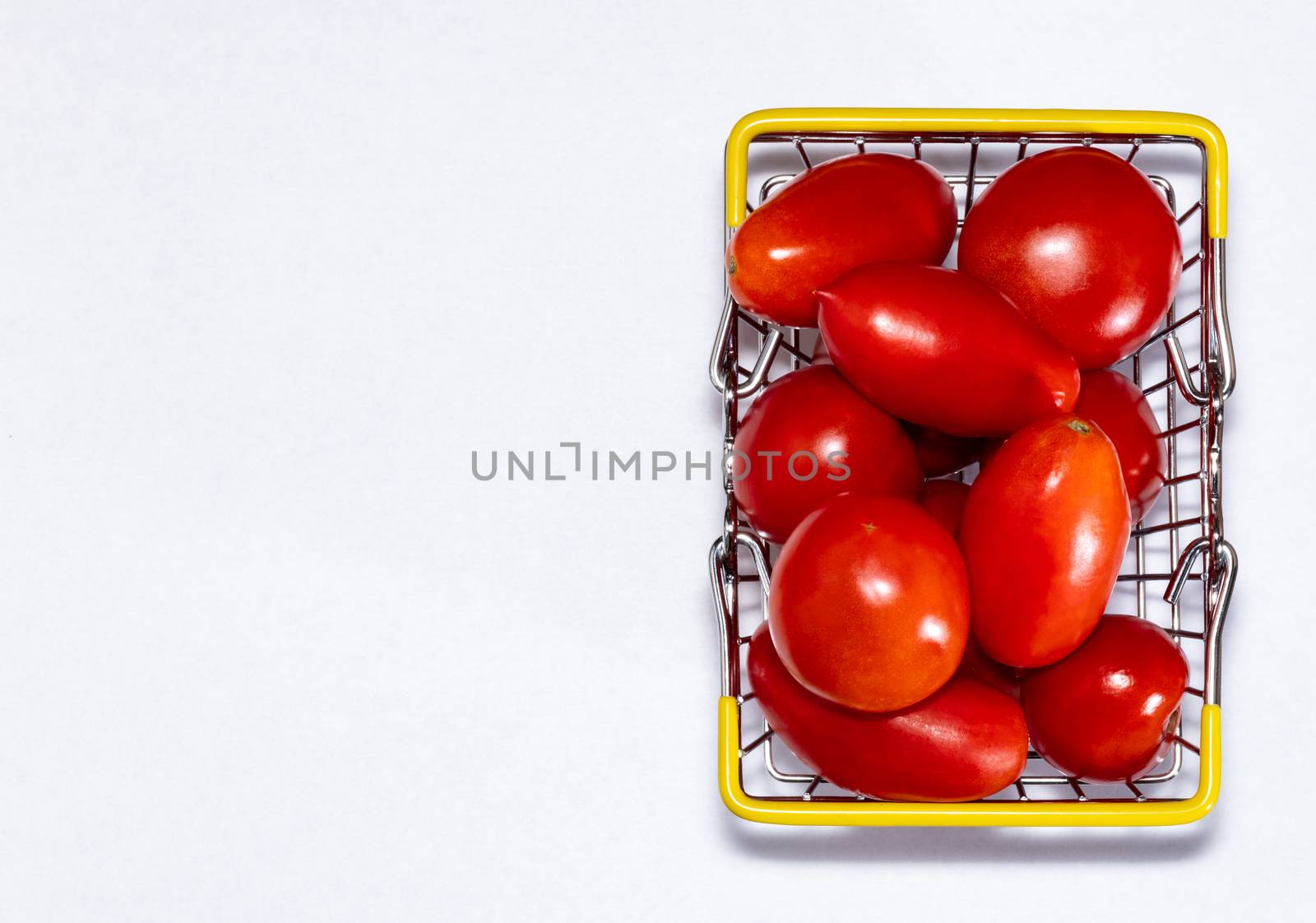Shot of tomatoes in shopping basket isolated on white background with copy space. Ripe tasty red tomatos in shopping basket. Top view. Tomato trading concept. Online shopping concept. Copy space.