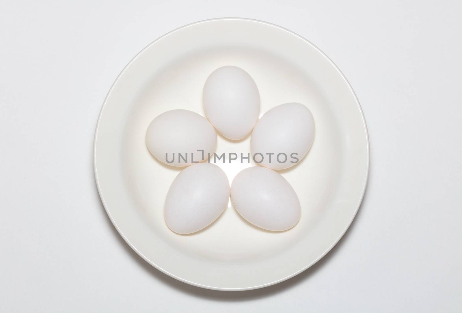 Fresh white eggs on a white plate. Top view. Cooking and dieting concept. White background. Close up shot. Isolated.