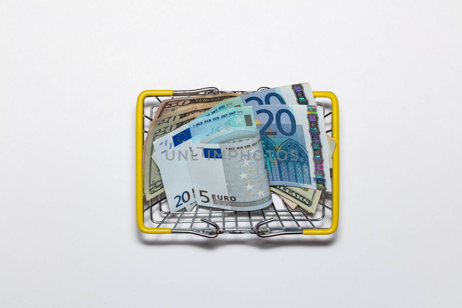 Dollar and euro bills mixed up in a basket for buyers on a white background. Isolated. Top view.