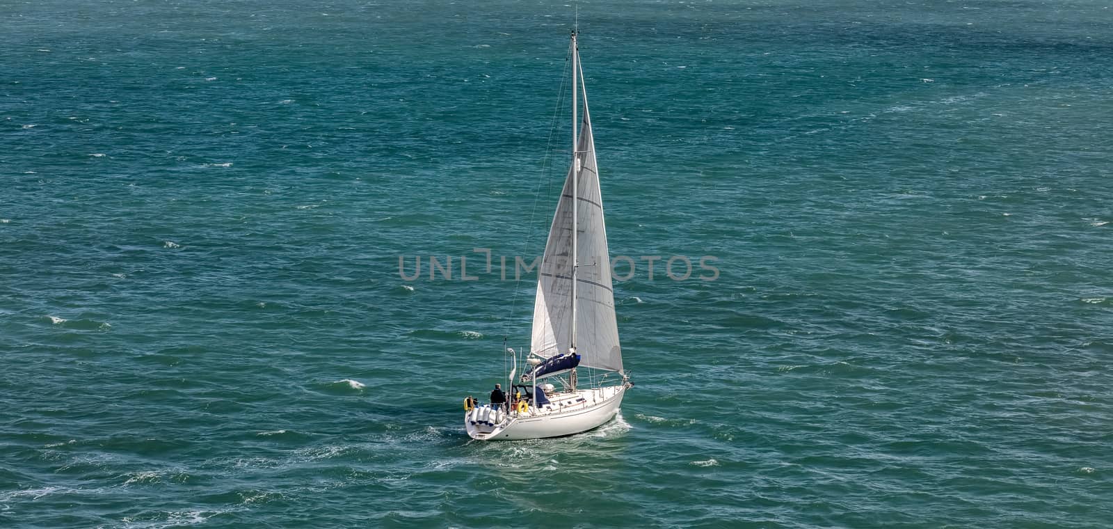 High angle shot of a white sailboat sailing in Weymouth Bay, UK. Sport and recreation concept.