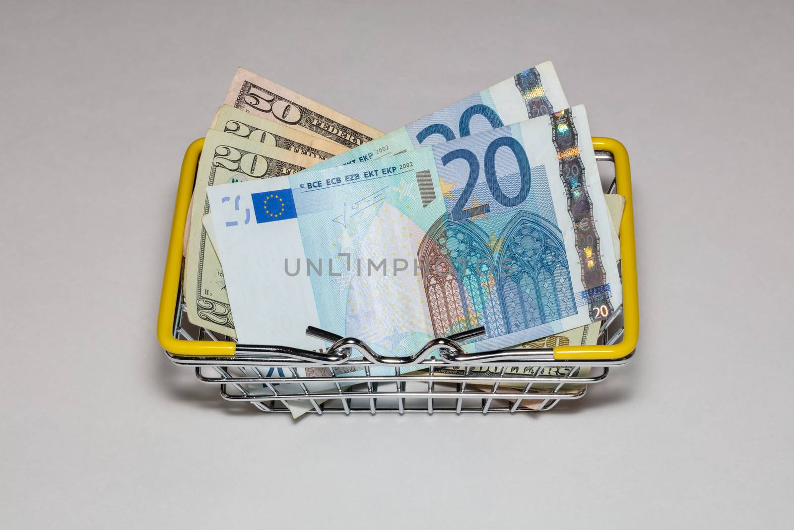 Dollar and euro bills mixed up in a basket for buyers on a white background. Isolated. High angle view.