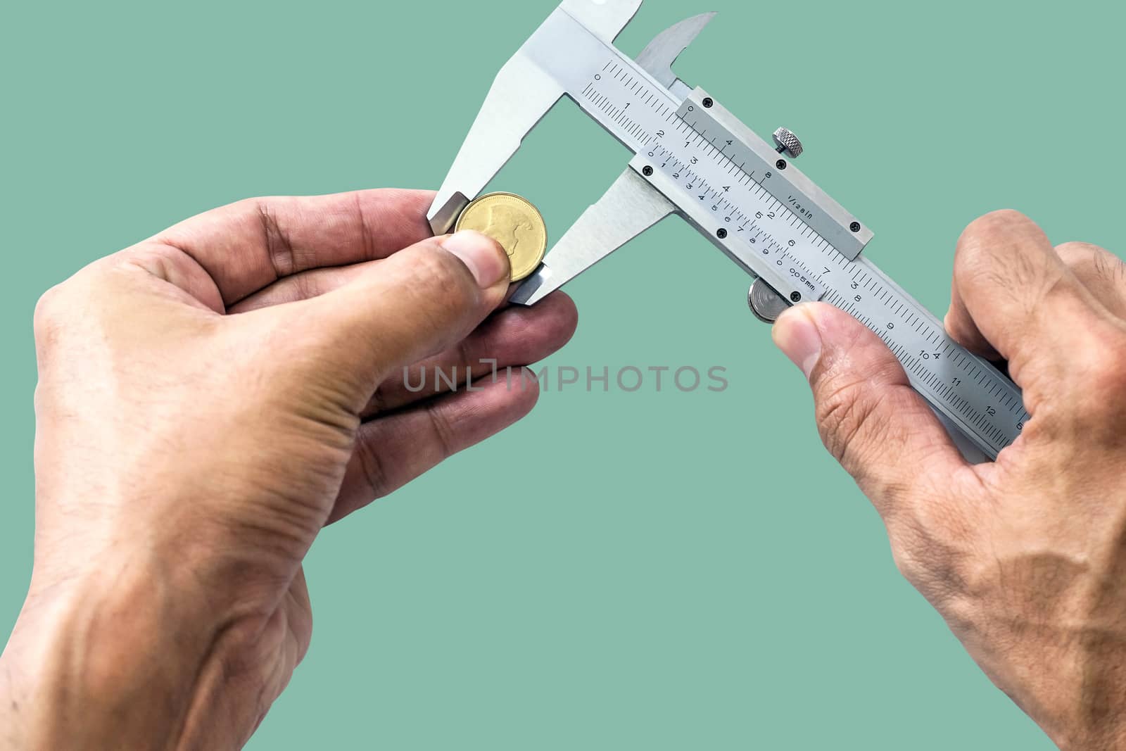 Closeup a man's hand is using Vernier to measure the size of a coin isolated on pastel color background.