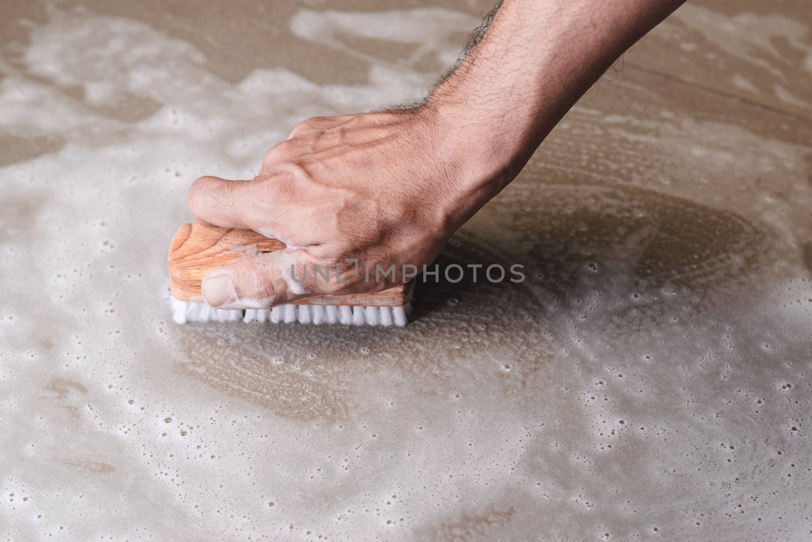 Men's hands are used to convert polishing cleaning on the tile floor.