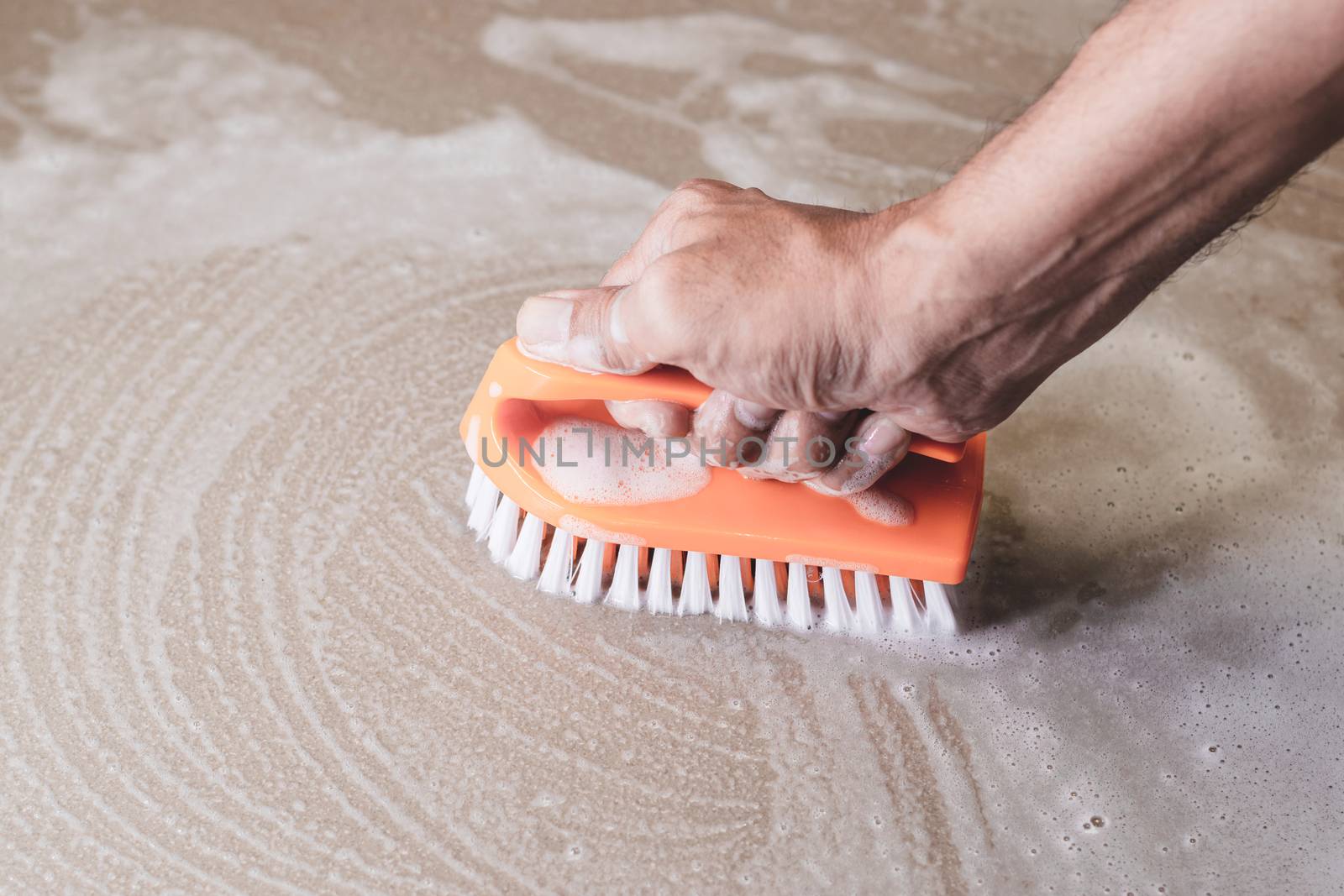 Men's hands are used to convert polishing cleaning on the tile floor.