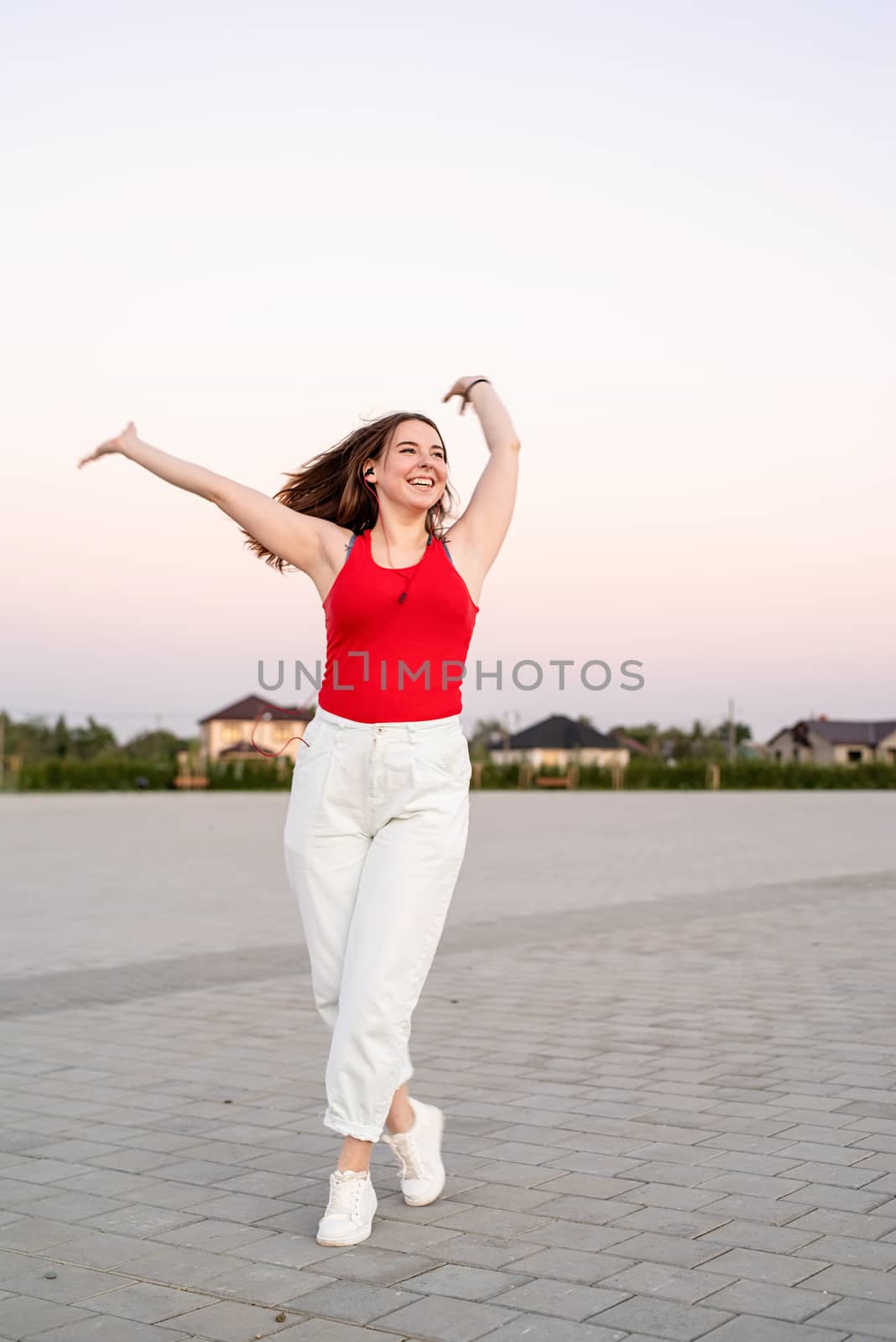 Active lifestyle. Teenage girl listening to the music dancing in the park