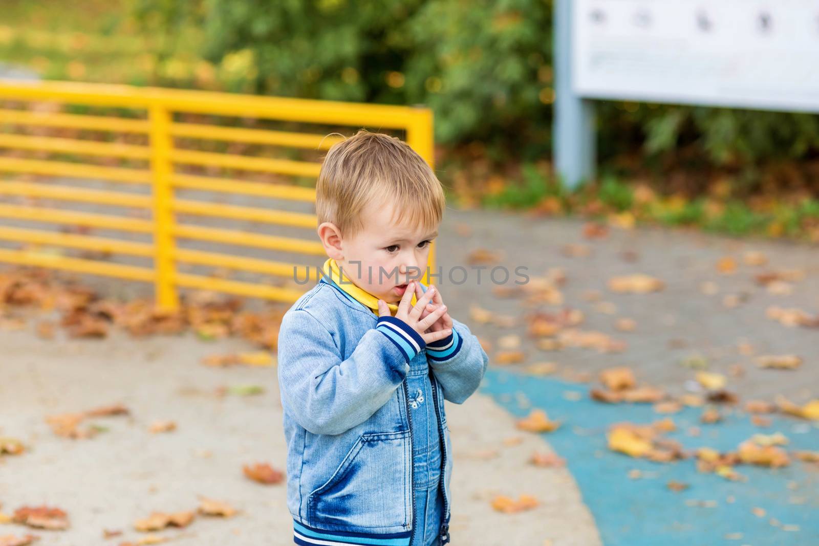 .A little boy stands scared alone in the middle of a playground in a park. by galinasharapova