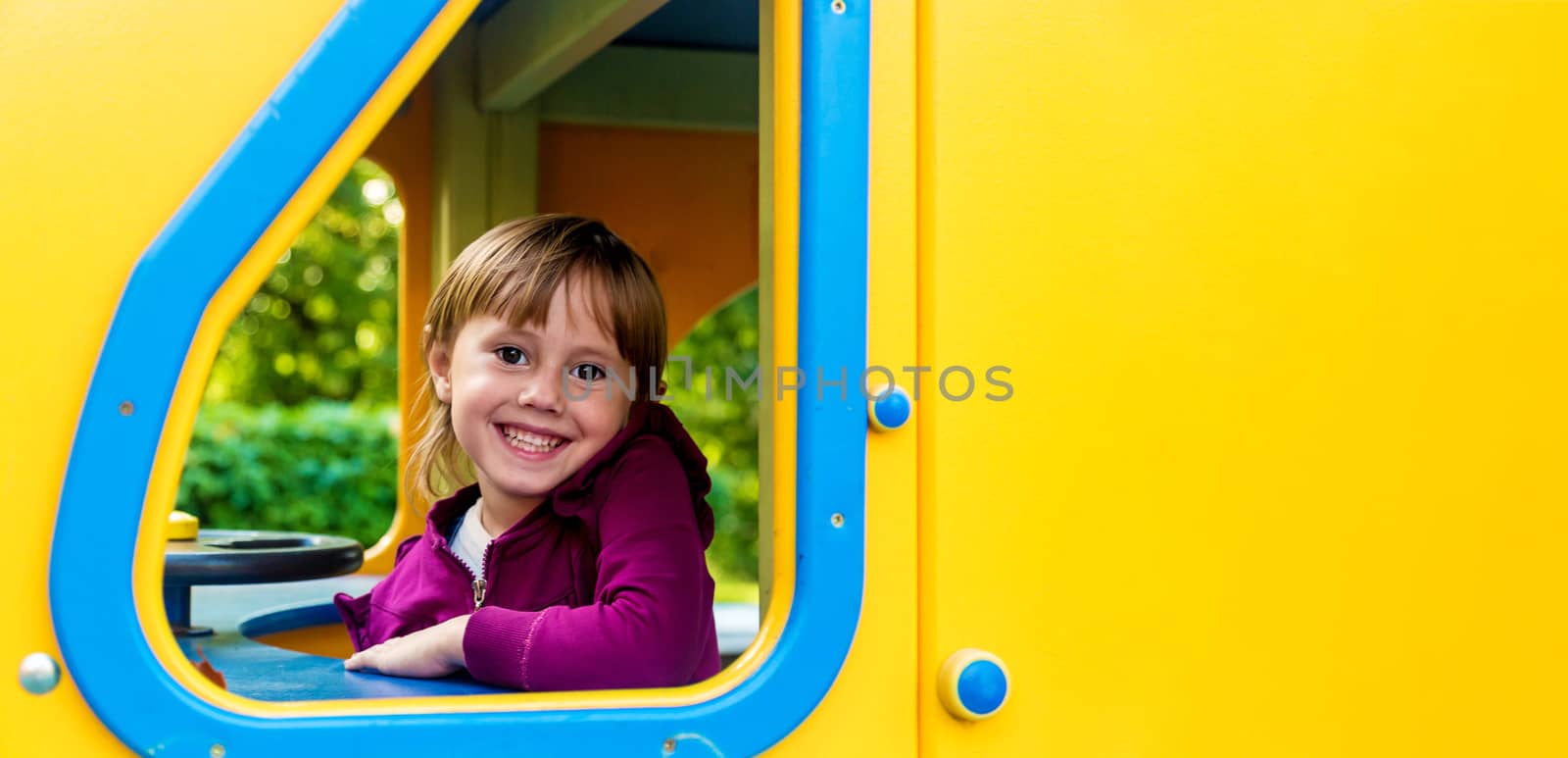 Cute little girl in dark pink clothes looking out from playground toy by galinasharapova