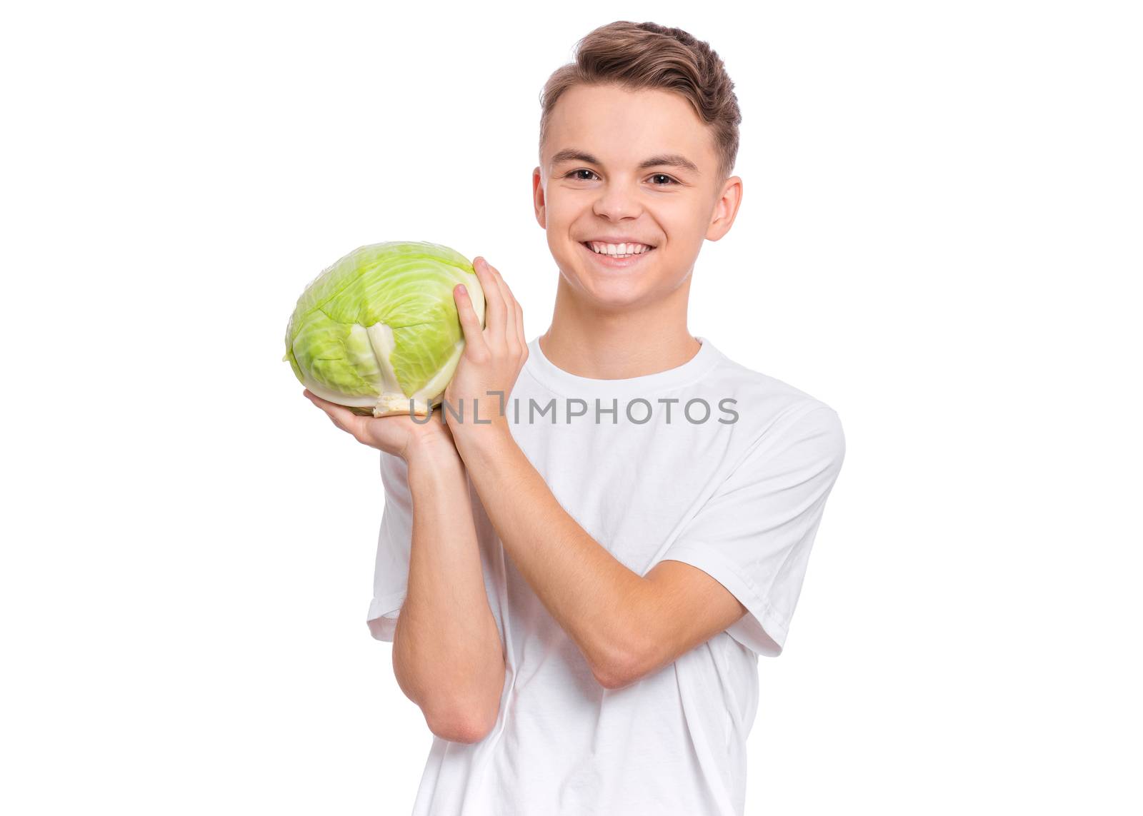 Portrait of handsome young teen boy holding fresh green cabbage and looking at camera, isolated on white background. Smiling child with healthy vegetables.