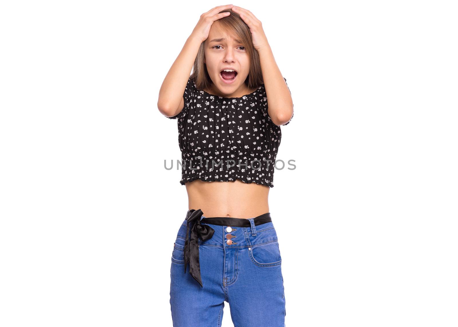 Surprised teen girl, isolated on white background. Child looking at camera in amazement, touching her head with hands. Beautiful caucasian teenager.