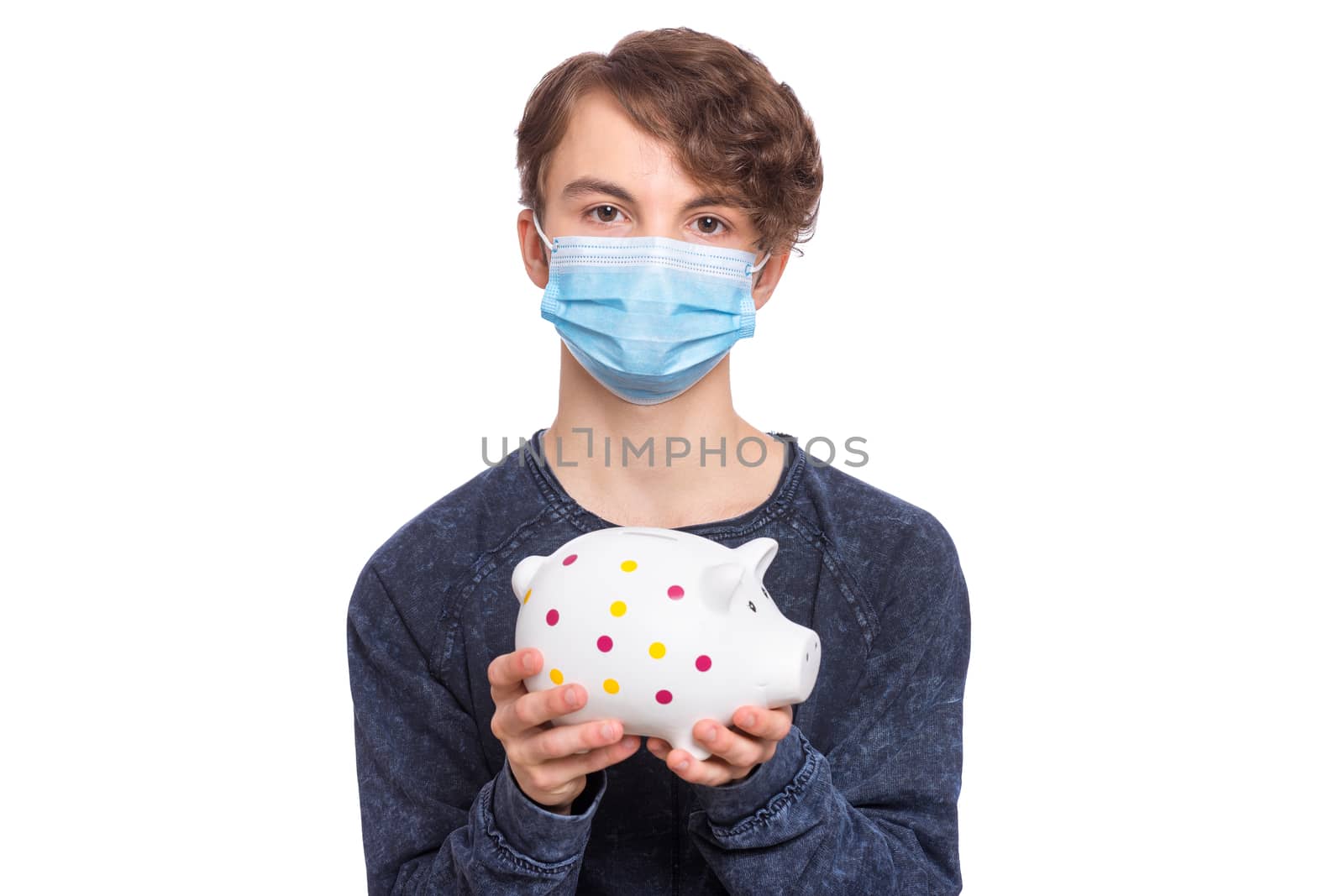 Concept of coronavirus quarantine. Portrait of teen boy wearing medical protective mask. Child holding Piggy Bank.