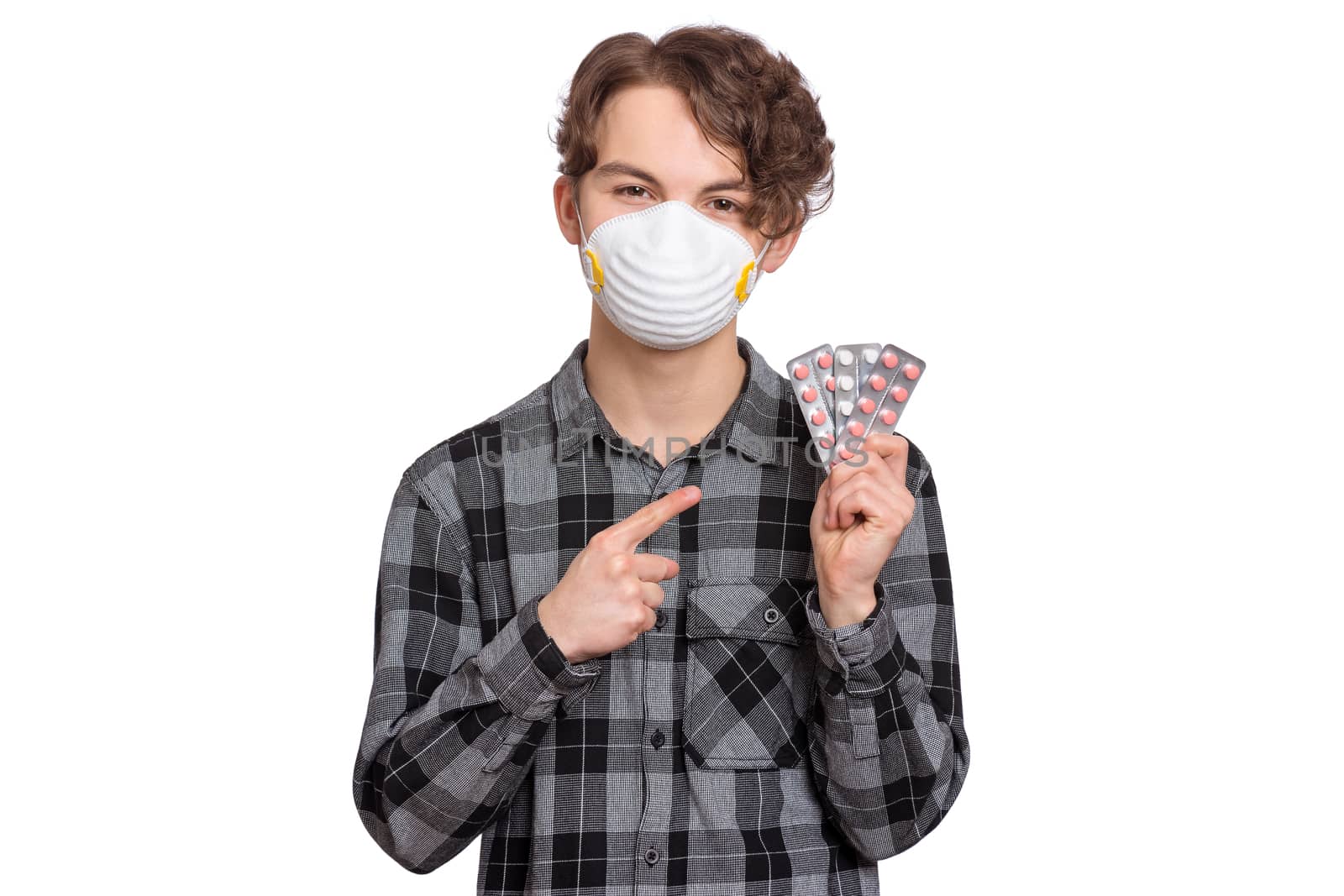 Concept of coronavirus quarantine. COVID-19 - home self isolation. Child wearing medical protective face mask to health protection from influenza virus, isolated on white. Teen boy holds pills.