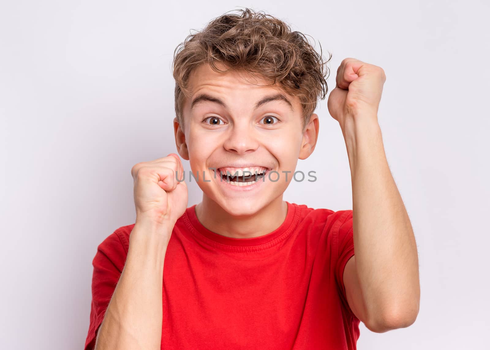 Portrait of teen boy happy and excited expressing winning gesture. Successful and celebrating victory, triumphant child on grey background.